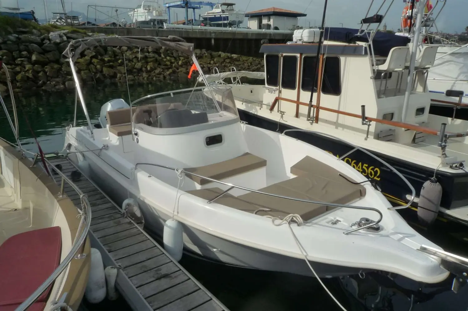B2 Marine Cap Ferret 672 — Bateau à moteur blanc amarré au ponton, vu de trois quarts avant.