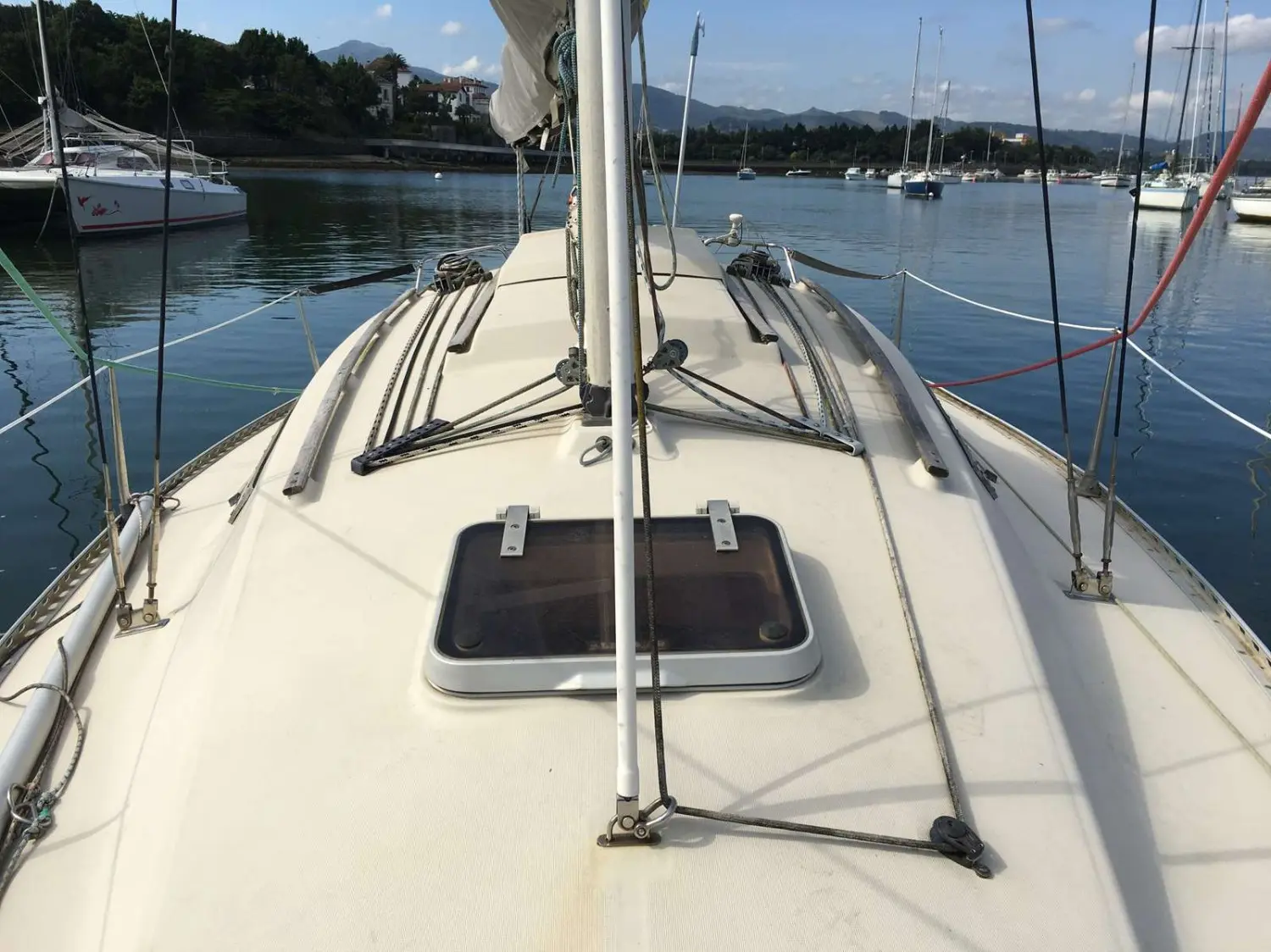 Beneteau First 26 — Vue du pont avant d’un voilier amarré, avec mât, gréement et panneau de pont.