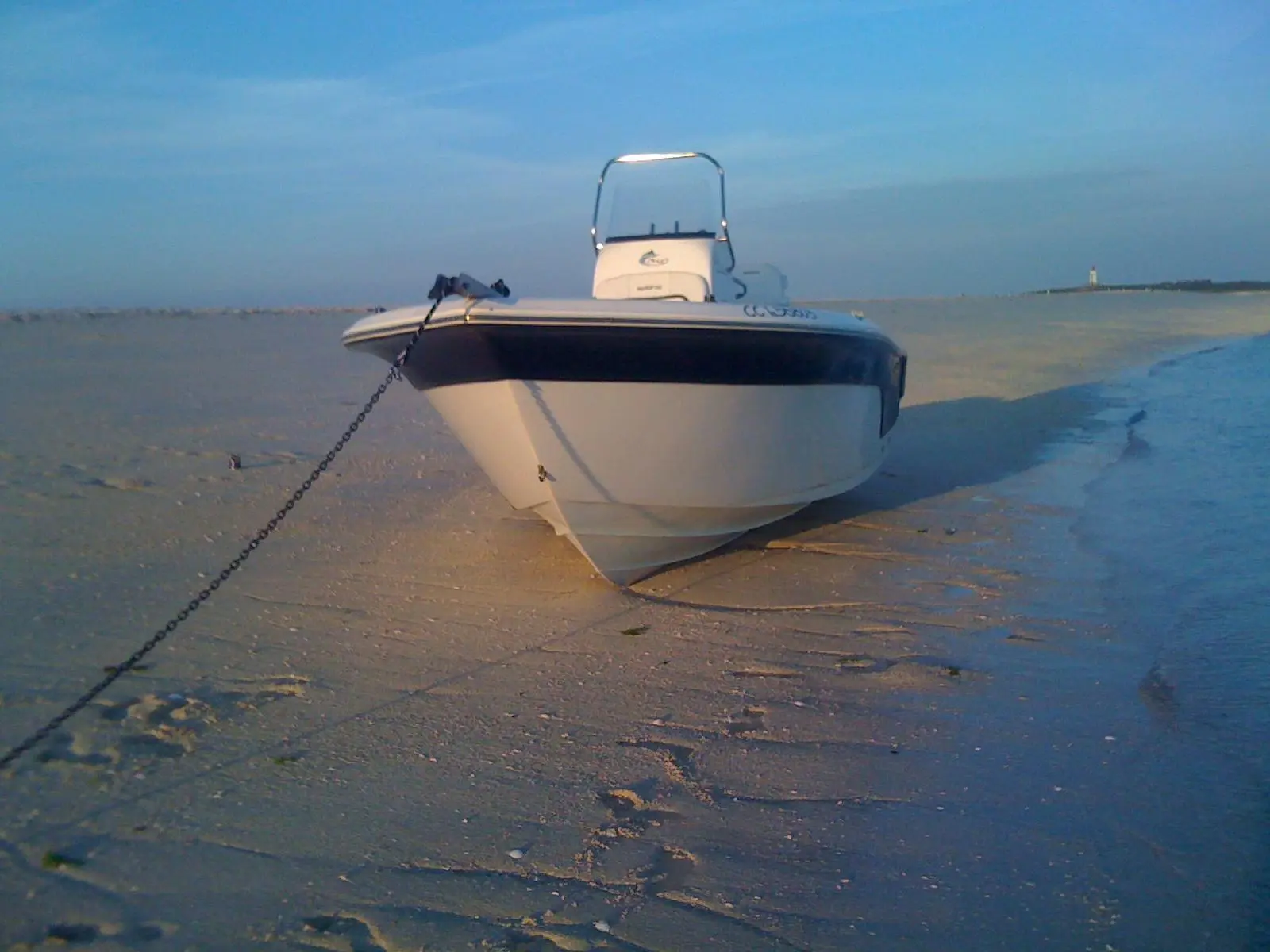 Sea Fox 216 CC — Bateau vu de face sur une plage à marée basse, relié à une chaîne.