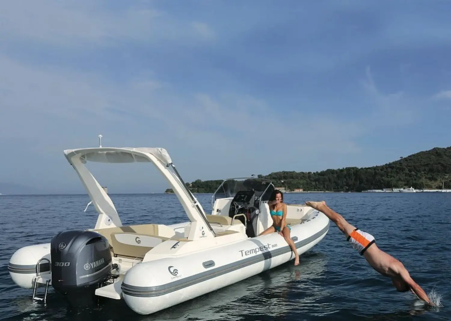 Capelli Tempest 800 — Bateau pneumatique blanc avec deux personnes dans l’eau près d’une côte.