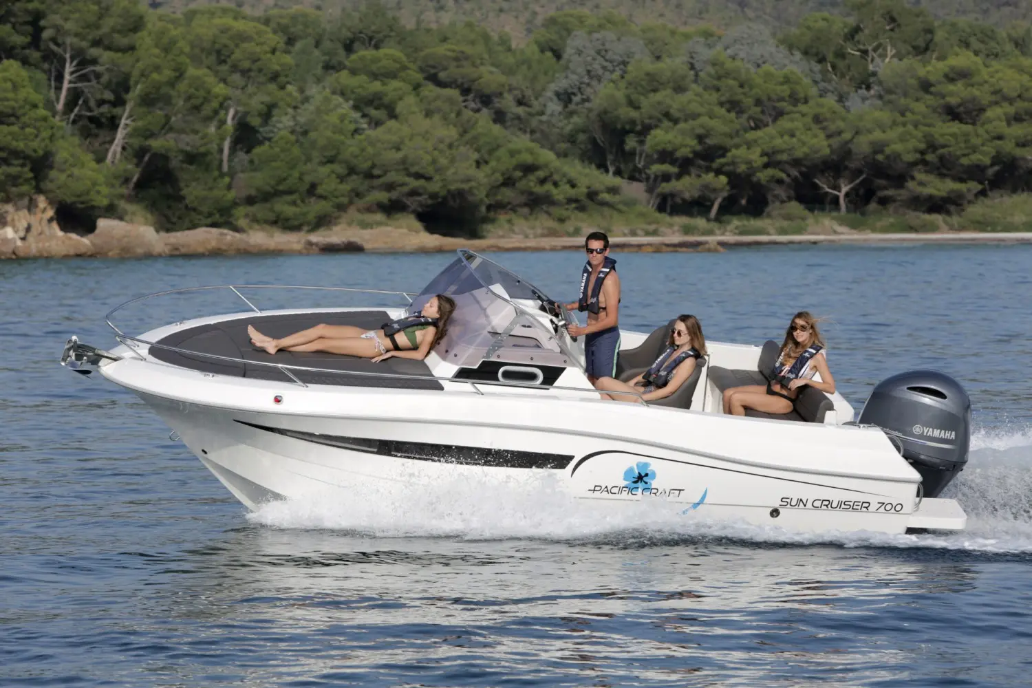 Pacific Craft 700 SC — Bateau à moteur blanc en navigation, photographié de profil avec plusieurs passagers.