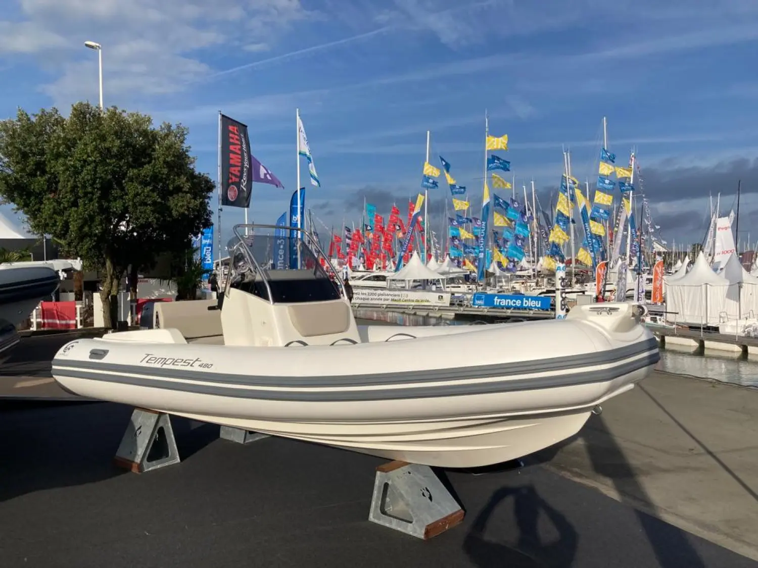 Capelli Tempest 480 — Semi-rigide blanc exposé sur bers, vu de profil dans un salon nautique.