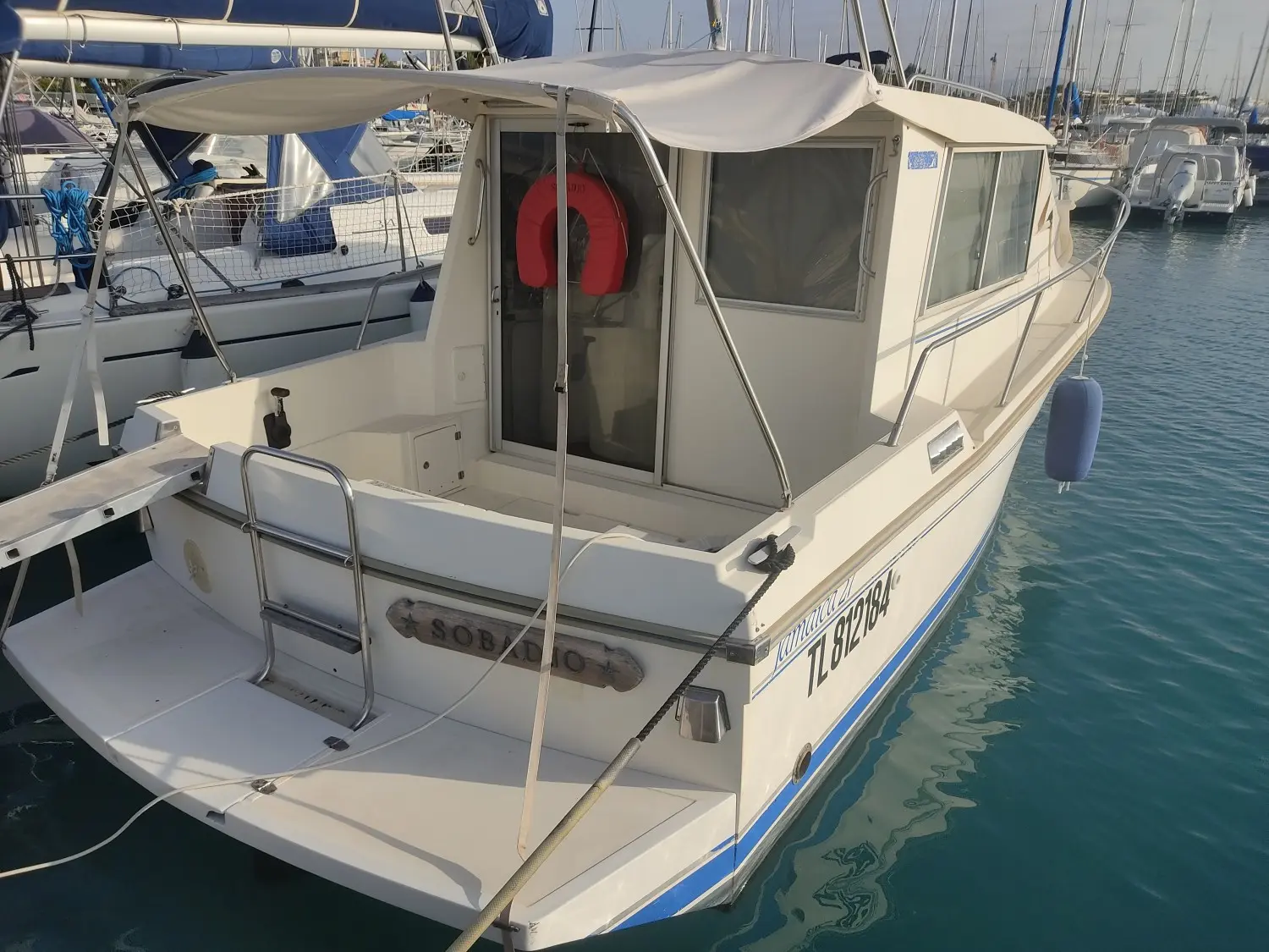 Gibert Marine Jamaica 27 — Bateau à moteur blanc amarré dans un port, vu de trois quarts arrière.
