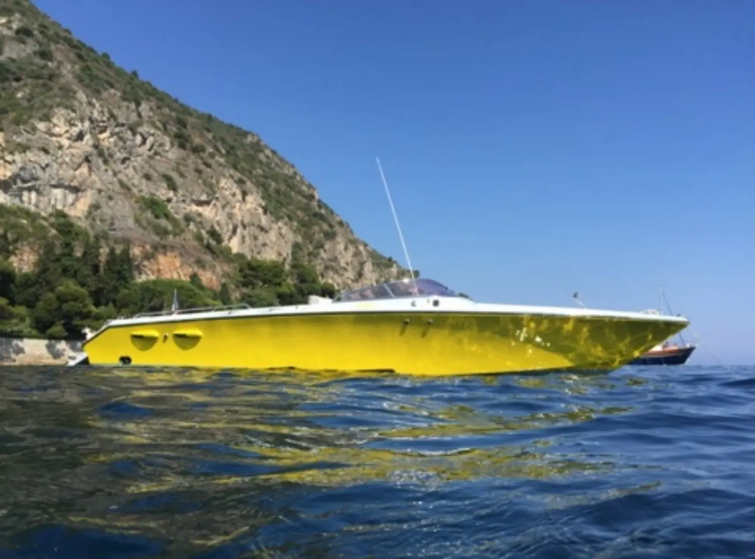 Offshore Marine Monte Carlo 30 — Bateau à moteur jaune photographié de profil près d'une côte rocheuse.