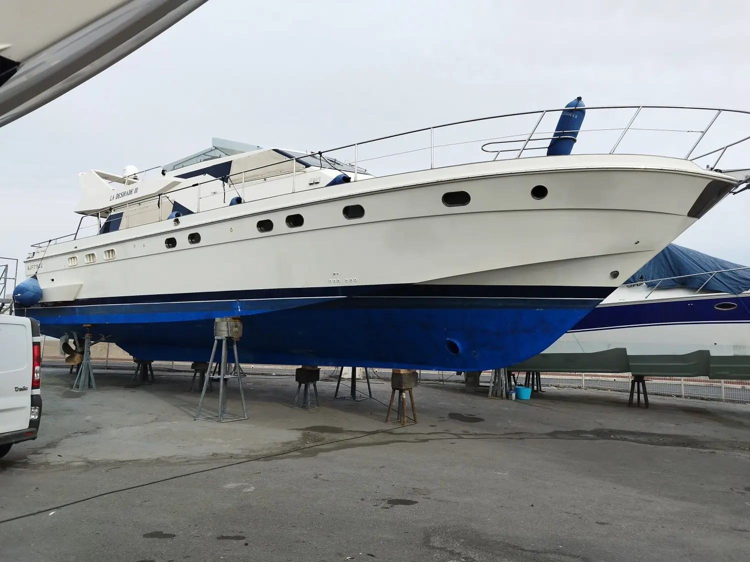 Guy Couach 1800 — Vedette à moteur blanche et bleue présentée sur bers dans un chantier naval.
