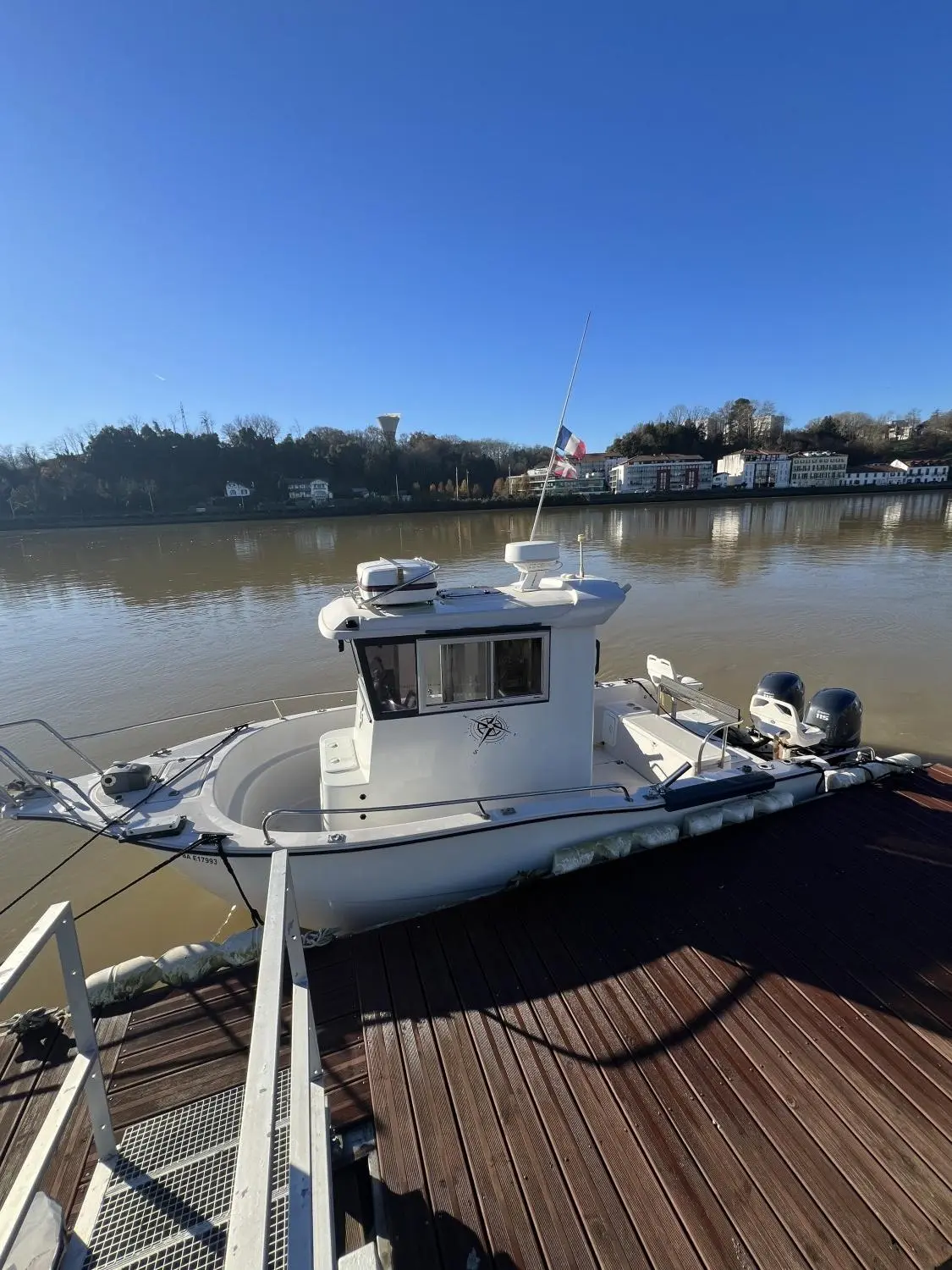 Acroplast Belouga Gwen — Bateau à cabine blanche amarré à un ponton, vu de trois quarts.