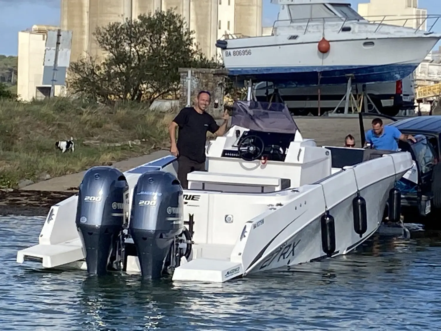 Pacific Craft 27 RX — Bateau à moteur blanc à double motorisation amarré, avec plusieurs personnes à bord.