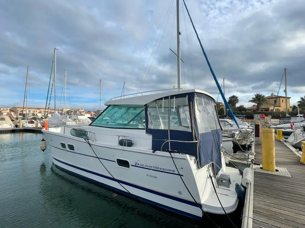 Delphia 1050 Escape — Bateau à moteur amarré dans un port de plaisance, vu de trois quarts arrière.