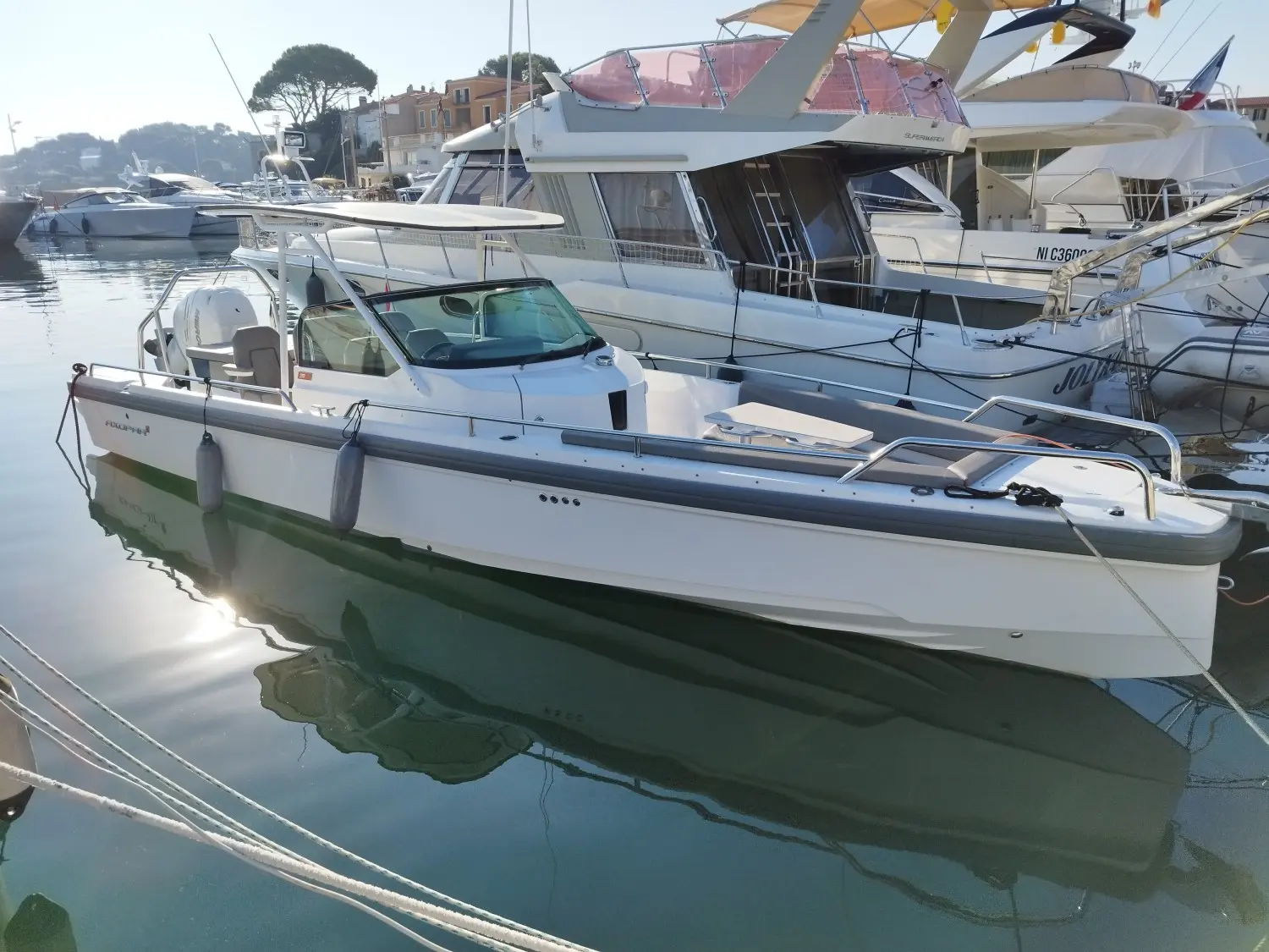 Axopar 28 T Top — Bateau à moteur blanc amarré dans un port, photographié de trois quarts.