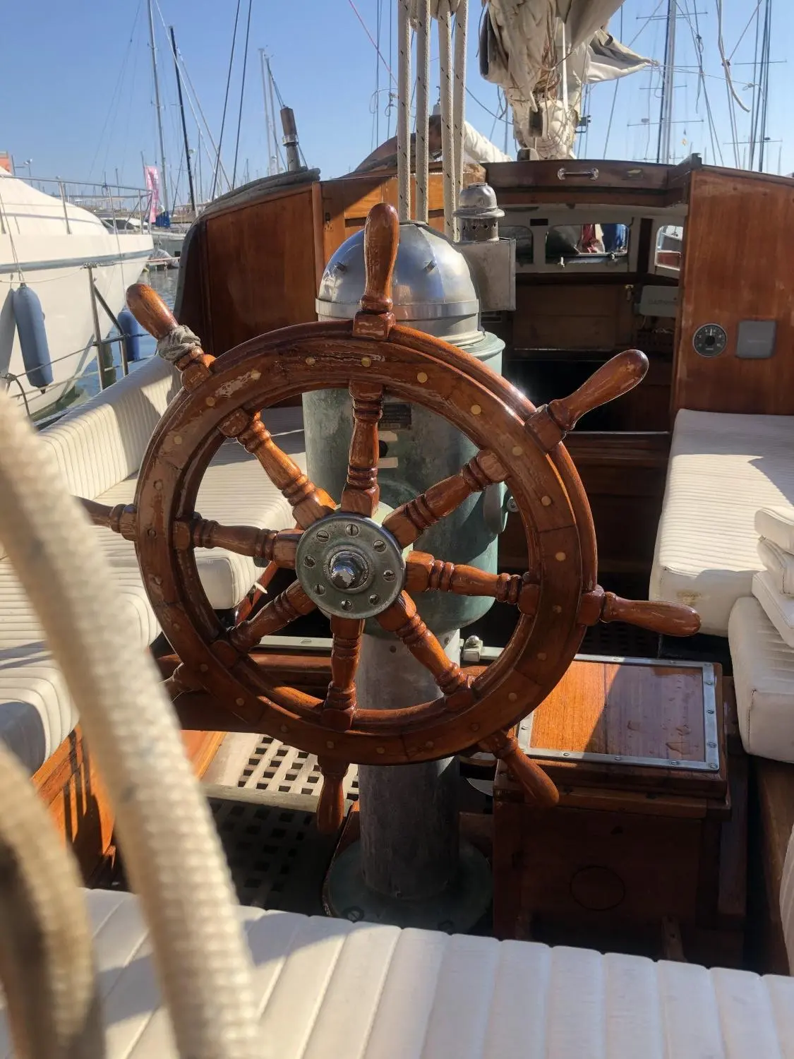 Matthiessen Yawl — Vue du cockpit en bois avec roue de gouvernail et cabine d’un voilier.