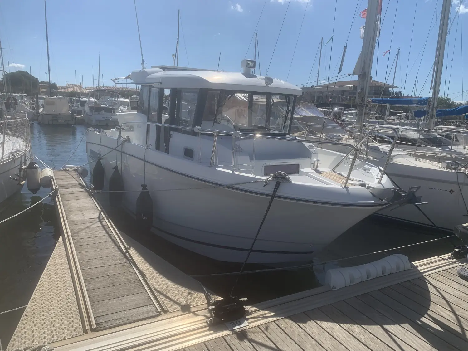 Jeanneau Merry Fisher 855 — Bateau à moteur blanc amarré dans un port de plaisance.