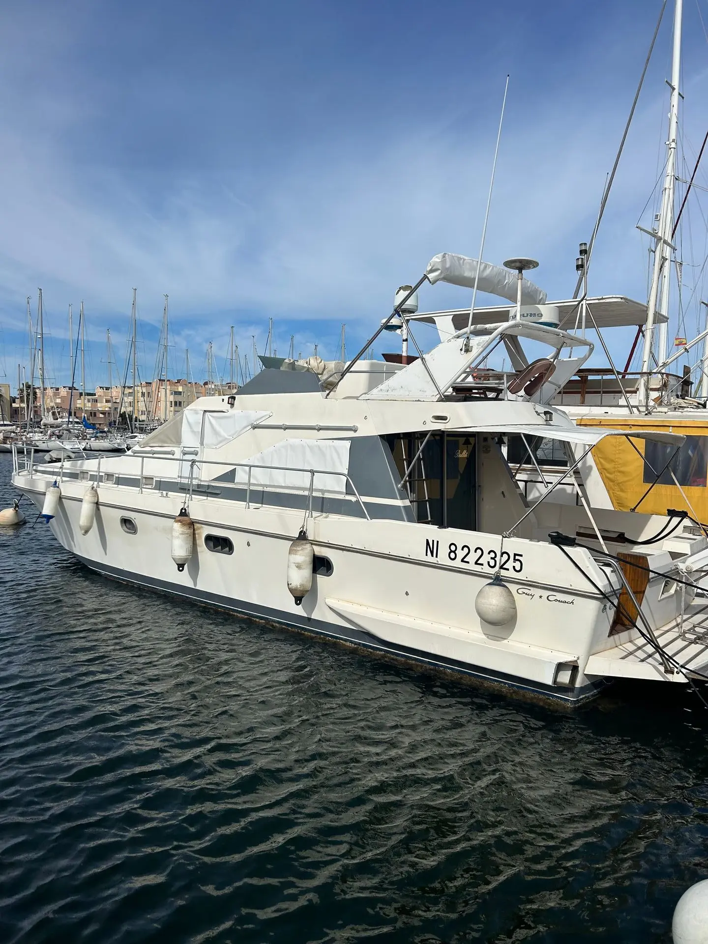 Guy Couach 1401 — Bateau à moteur blanc vu de trois quarts dans un port de plaisance.