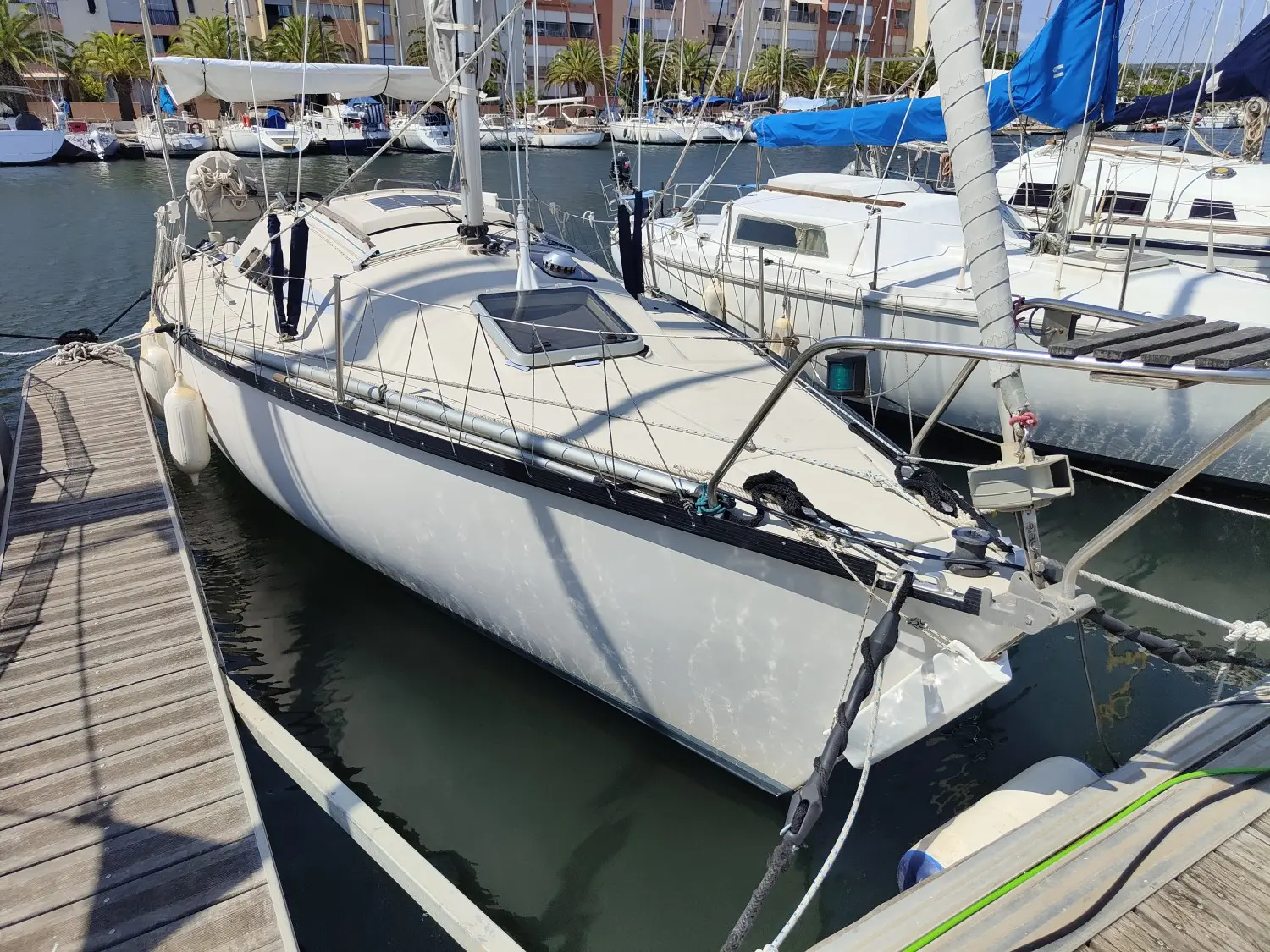 Beneteau First 25 — Voilier blanc amarré au ponton, photographié de trois quarts avant.