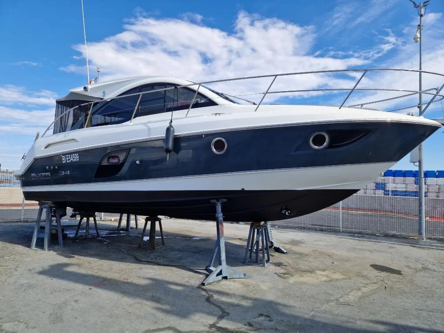 Beneteau Flyer Gran Turismo 34 — Vue de trois quarts d’un bateau à moteur blanc et bleu, posé sur des bers.