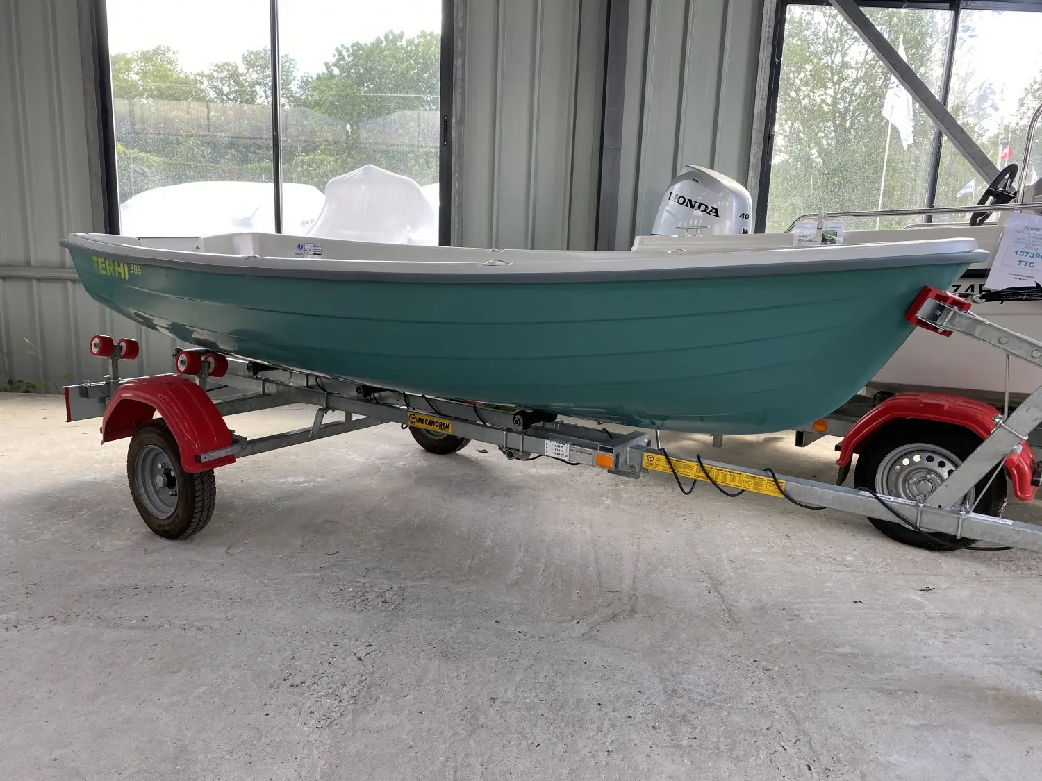 Terhi 385 — Bateau vert présenté sur une remorque dans un espace couvert, vu de profil.