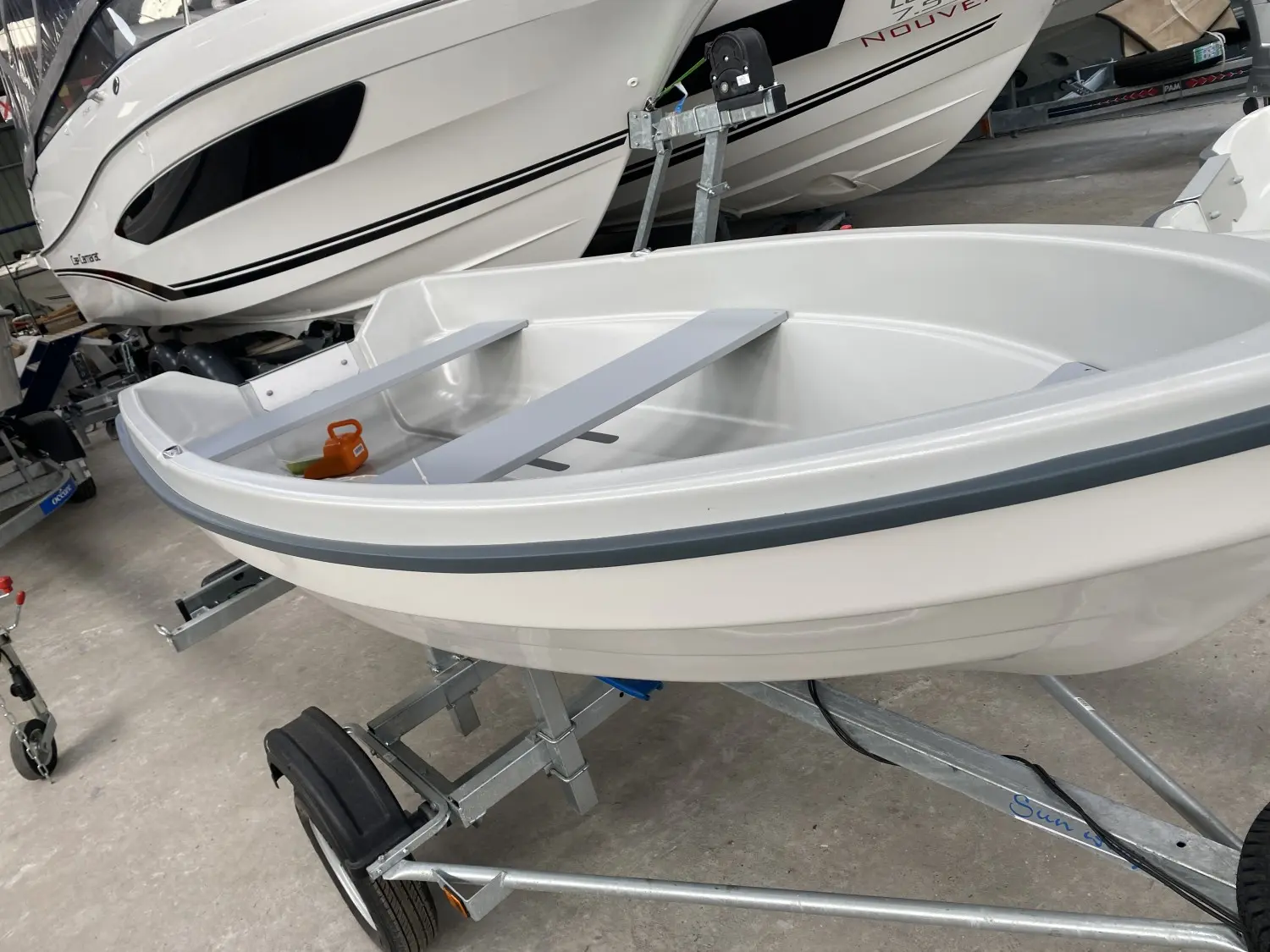 Terhi Sunny — Petit bateau blanc ouvert présenté sur une remorque dans un hangar.