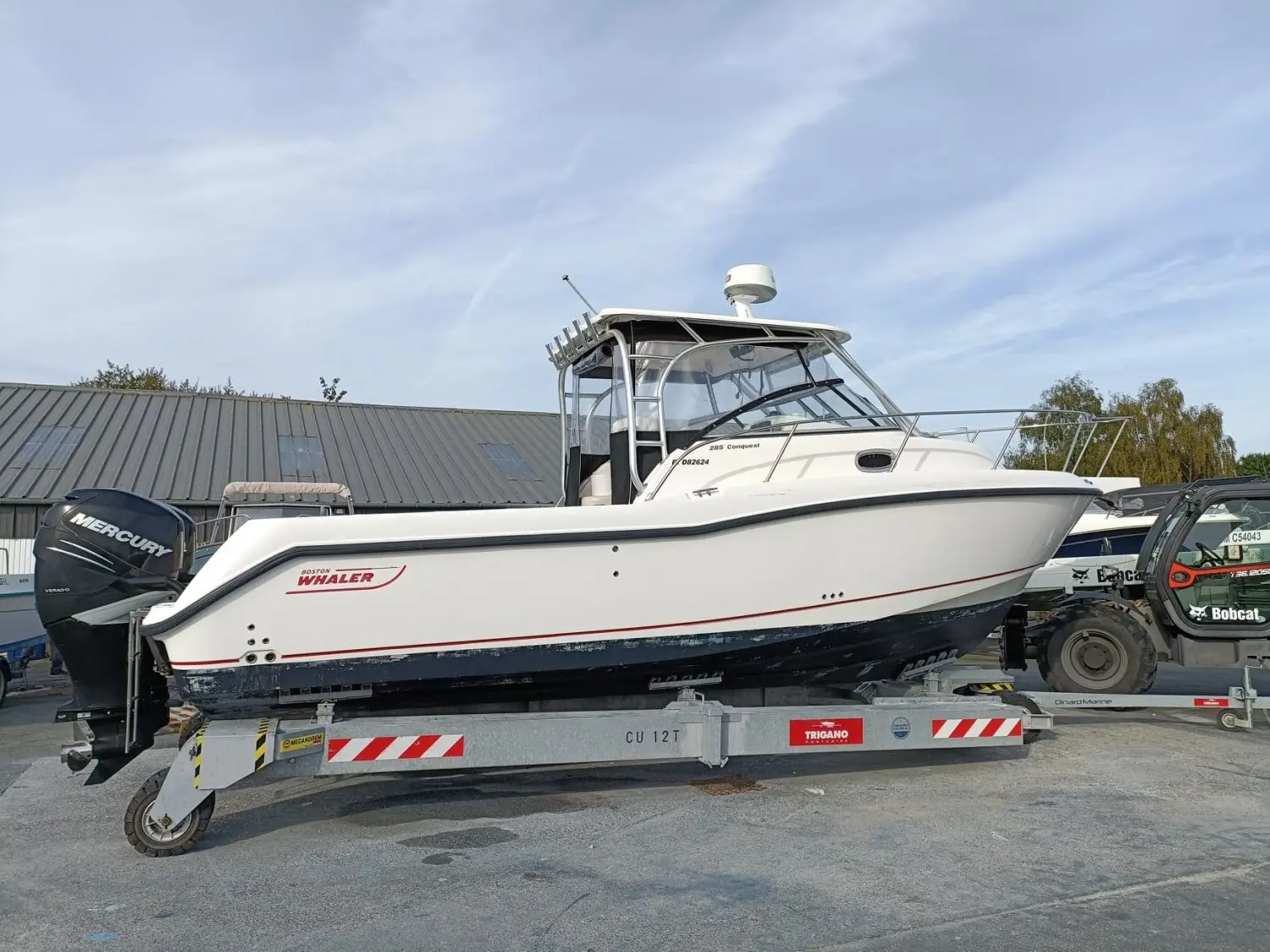 Boston Whaler 285 Conquest — Bateau blanc à cabine, photographié de profil sur sa remorque.
