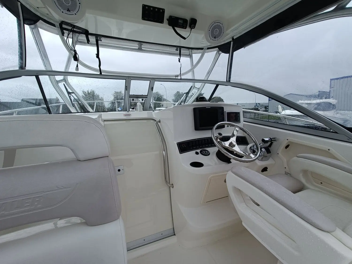 Boston Whaler 285 Conquest — Vue du poste de pilotage et des sièges sous la console fermée.