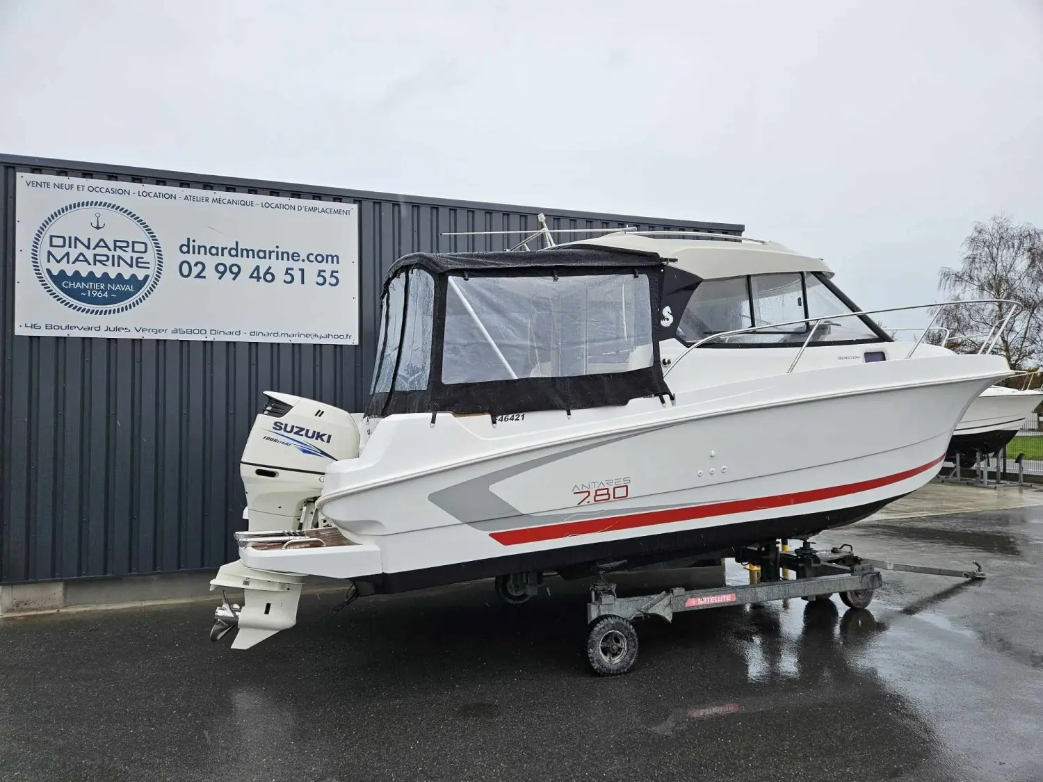 Beneteau Antares 780 HB — Bateau à moteur blanc sur remorque, photographié de trois quarts devant un hangar.