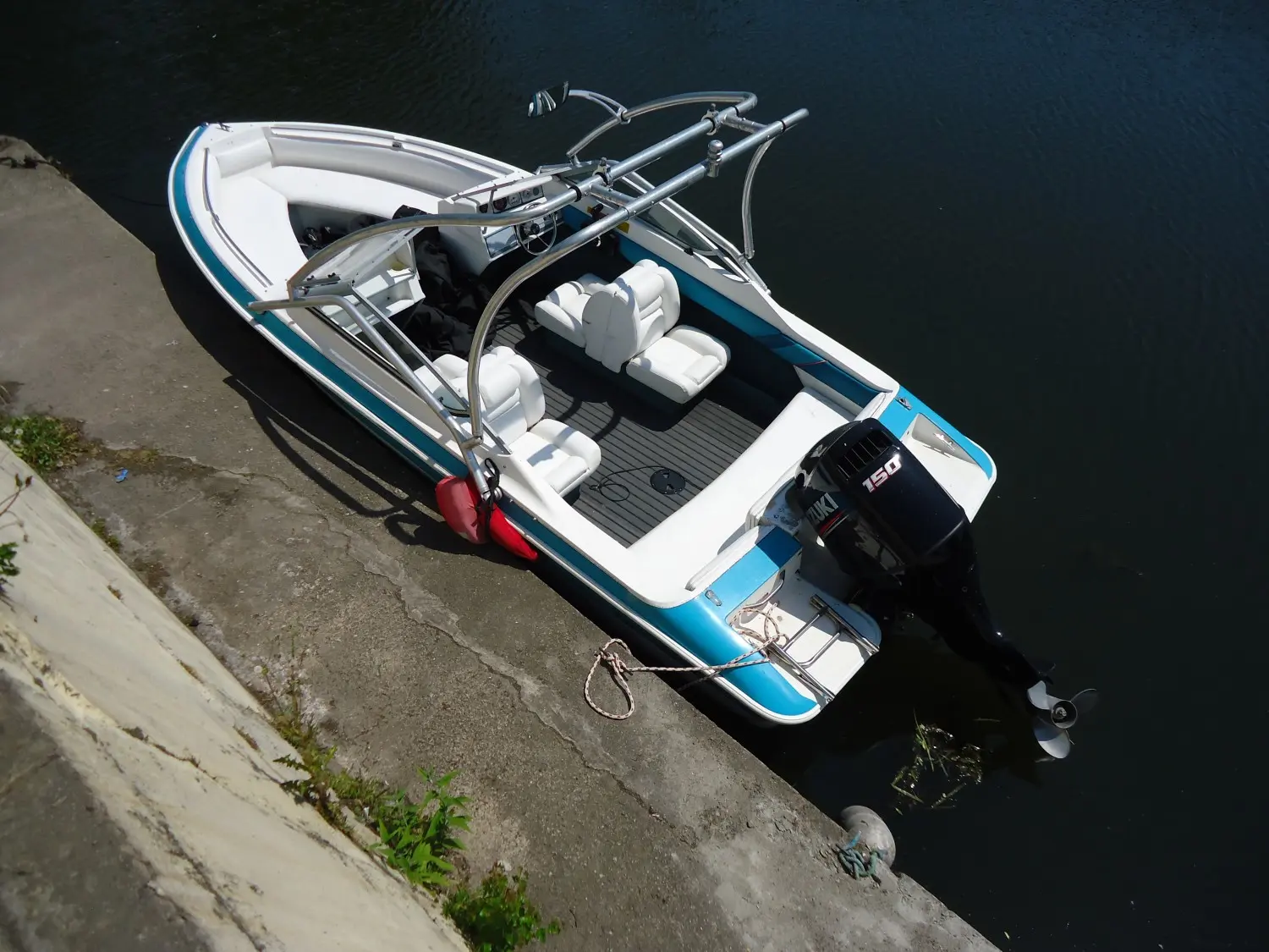 Larson All American 190 — Vue en plongée d’un bateau à moteur bleu et blanc amarré au quai.