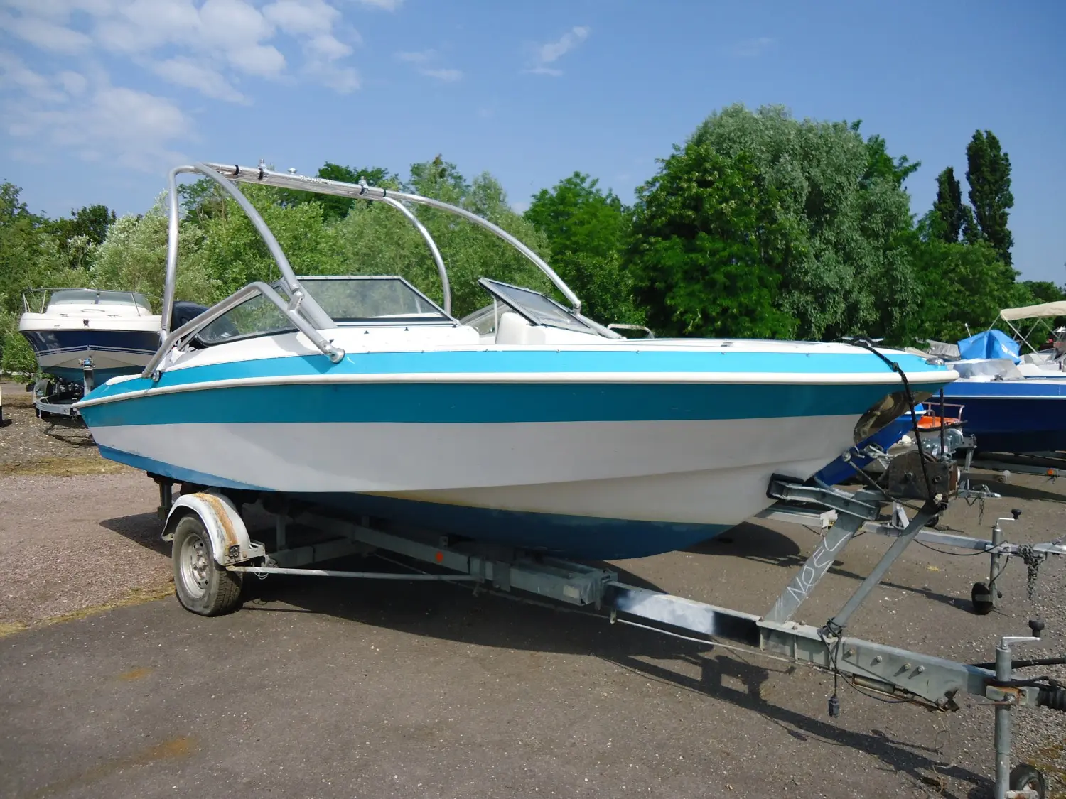 Larson All American 190 — Bateau à moteur blanc et bleu présenté sur sa remorque dans un port à sec.