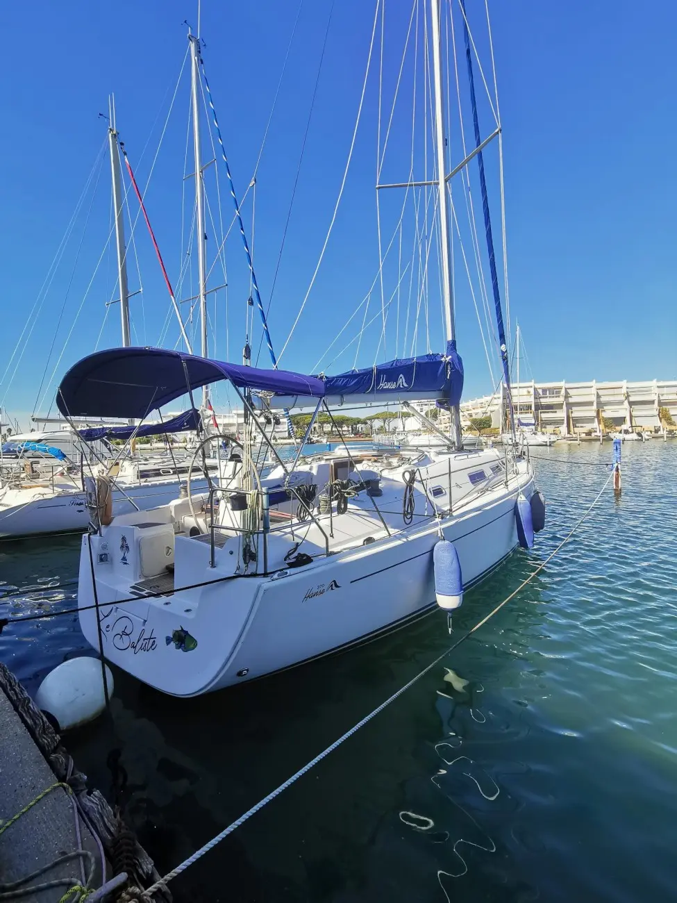 Hanse 370 — Voilier blanc amarré dans une marina, vu de trois quarts arrière.