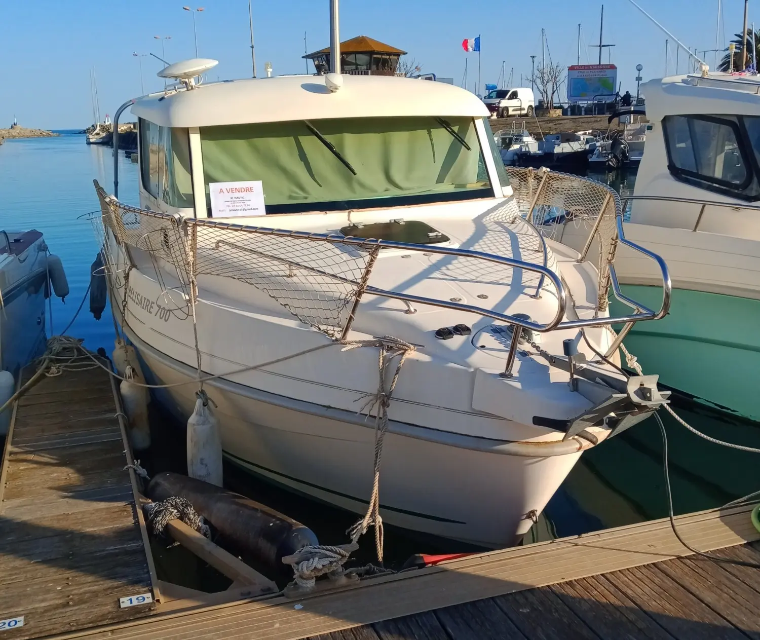 Mery Nautic Belisaire 700 — Bateau à moteur amarré dans un port, vu de trois quarts avant.