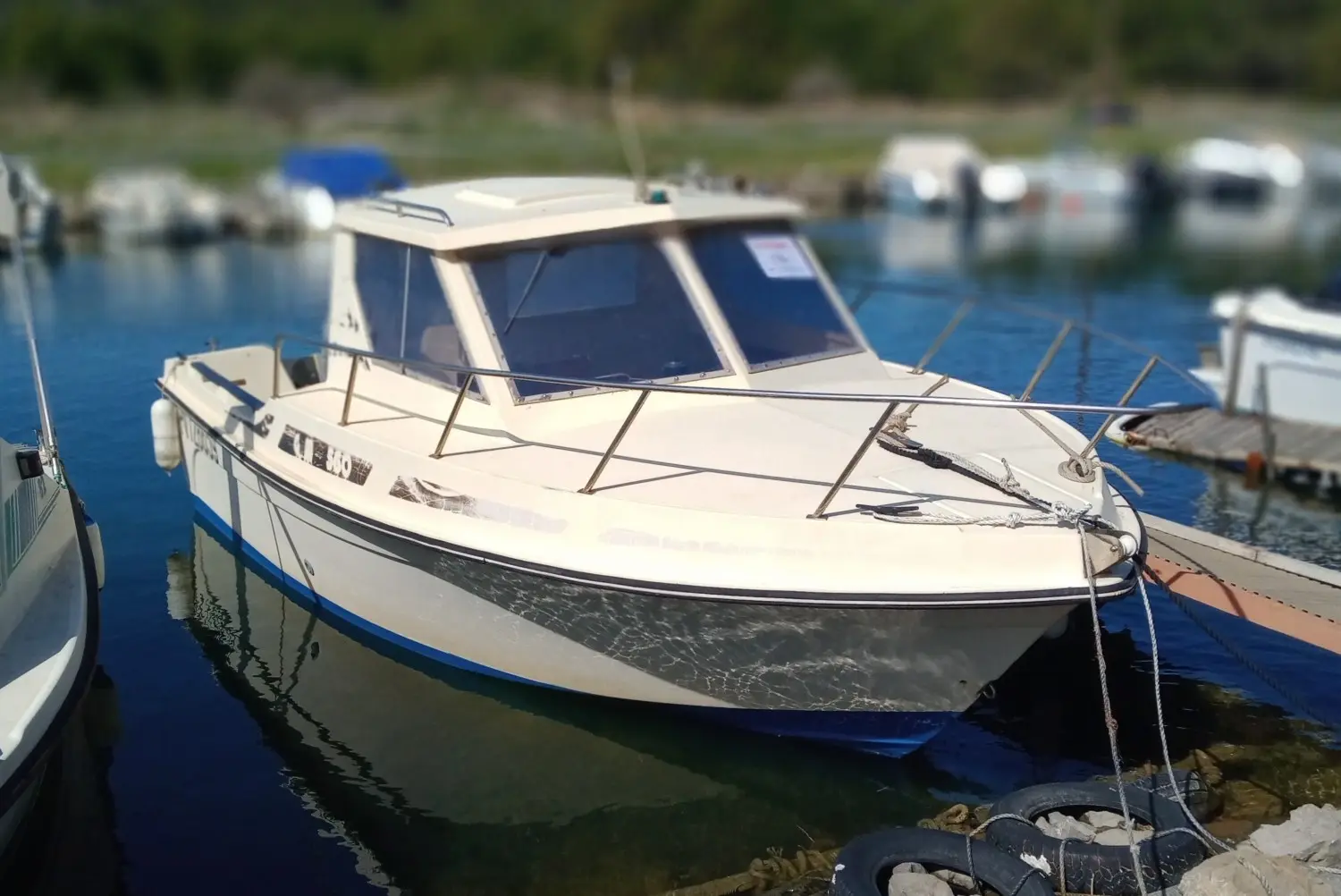 Guymarine GM 560 — Bateau à moteur blanc amarré dans une marina, vu de trois quarts avant.