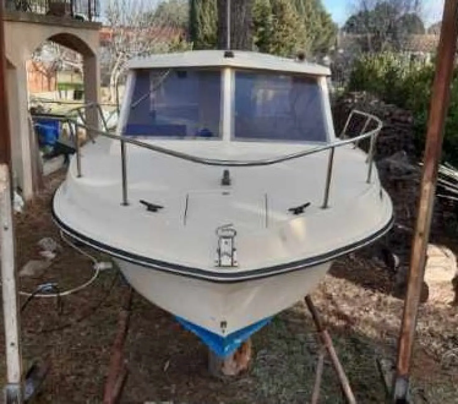 Guymarine GM 560 — Bateau blanc à cabine photographié de face, posé sur cales dans un jardin.