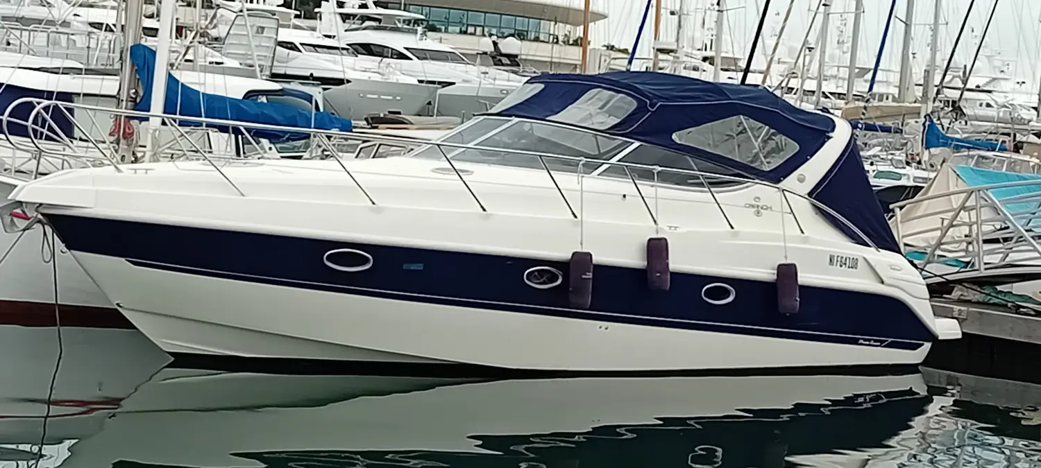 Cranchi Zaffiro 34 — Bateau à moteur blanc et bleu amarré dans un port de plaisance.
