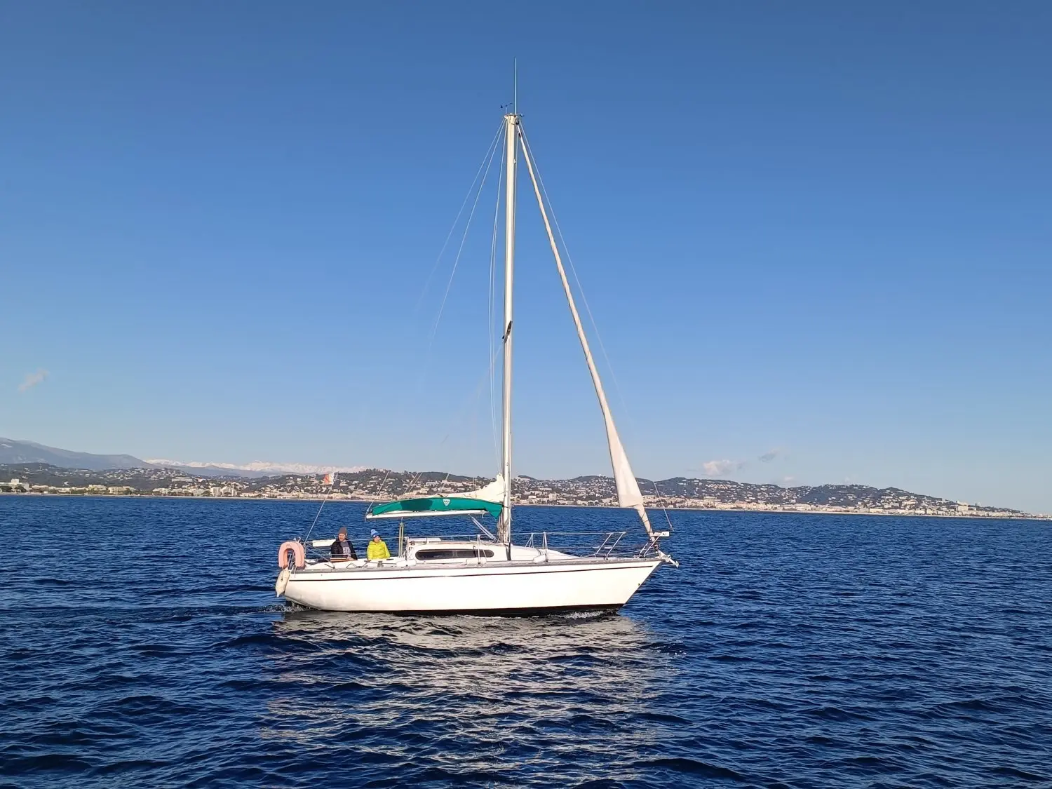 Kelt 8M — Voilier blanc vu de profil sur l’eau, avec deux personnes à bord.