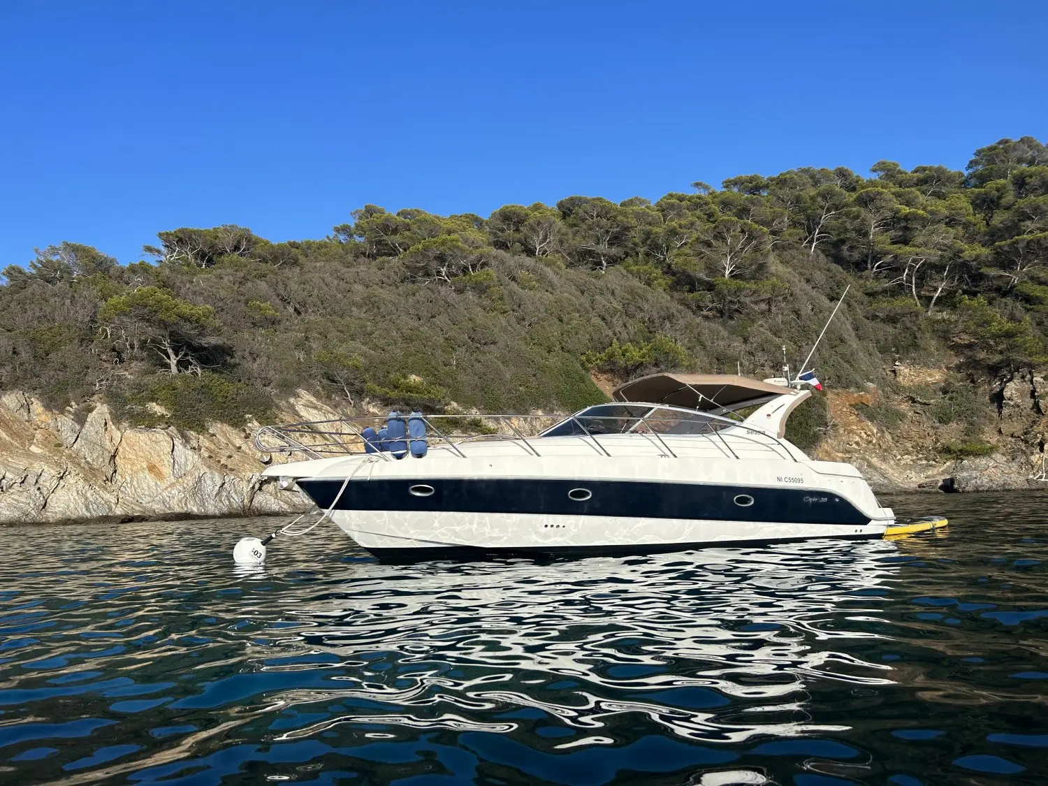 Sessa Marine Oyster 35 — Bateau à moteur vu de profil au mouillage devant une côte rocheuse.