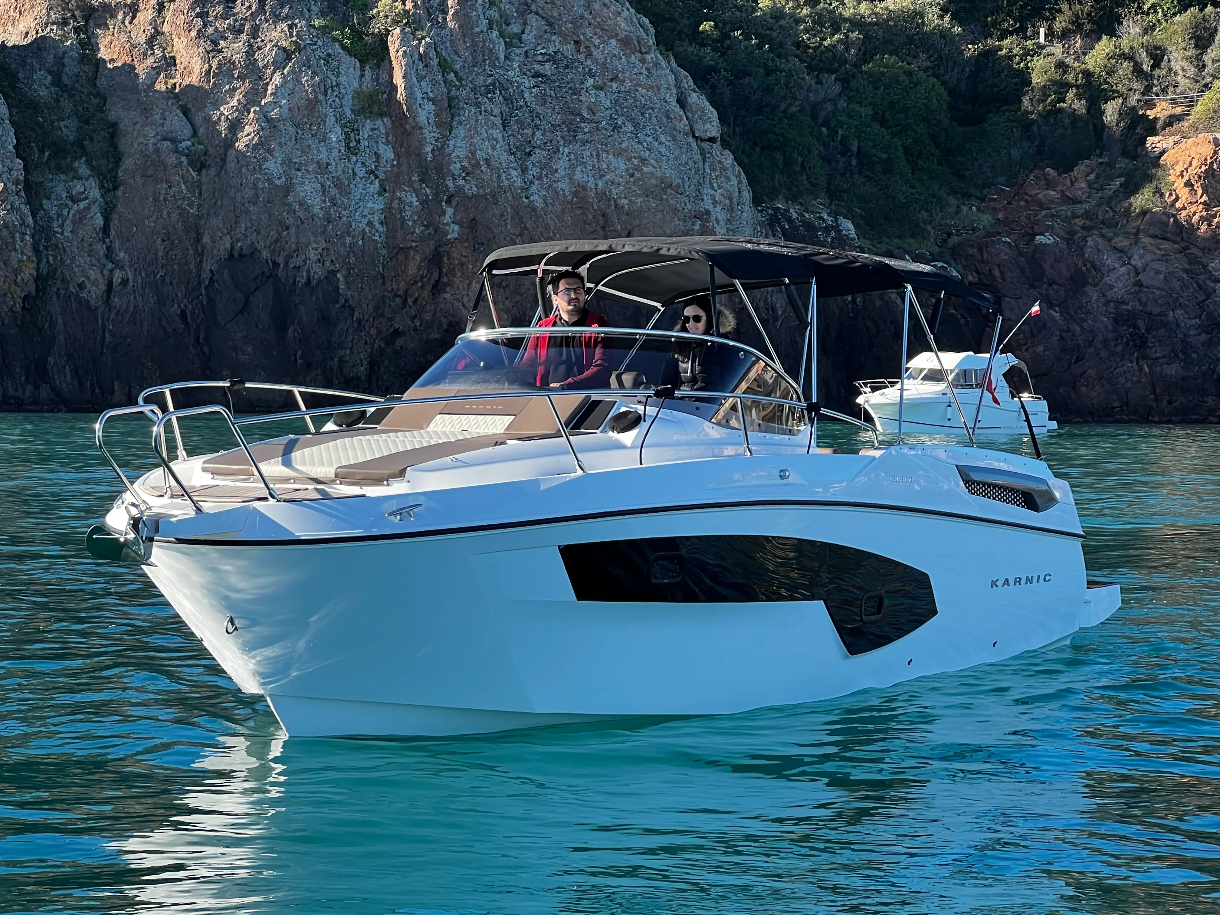 Karnic SL800 — Bateau à moteur blanc vu de trois-quarts dans une crique, avec deux personnes à bord.