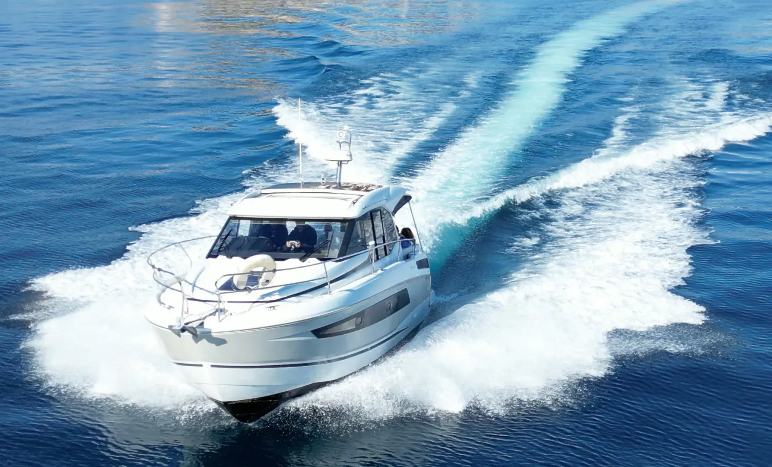 Jeanneau NC 33 — Bateau à moteur blanc naviguant à vive allure, vu de trois quarts avant.