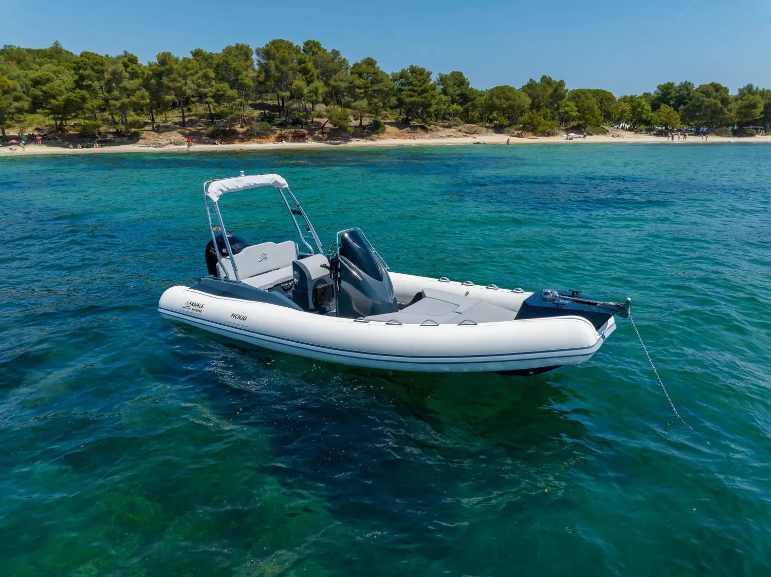 Fanale Pichju 600 — Semi-rigide blanc vu de trois quarts sur une eau turquoise, près du rivage.
