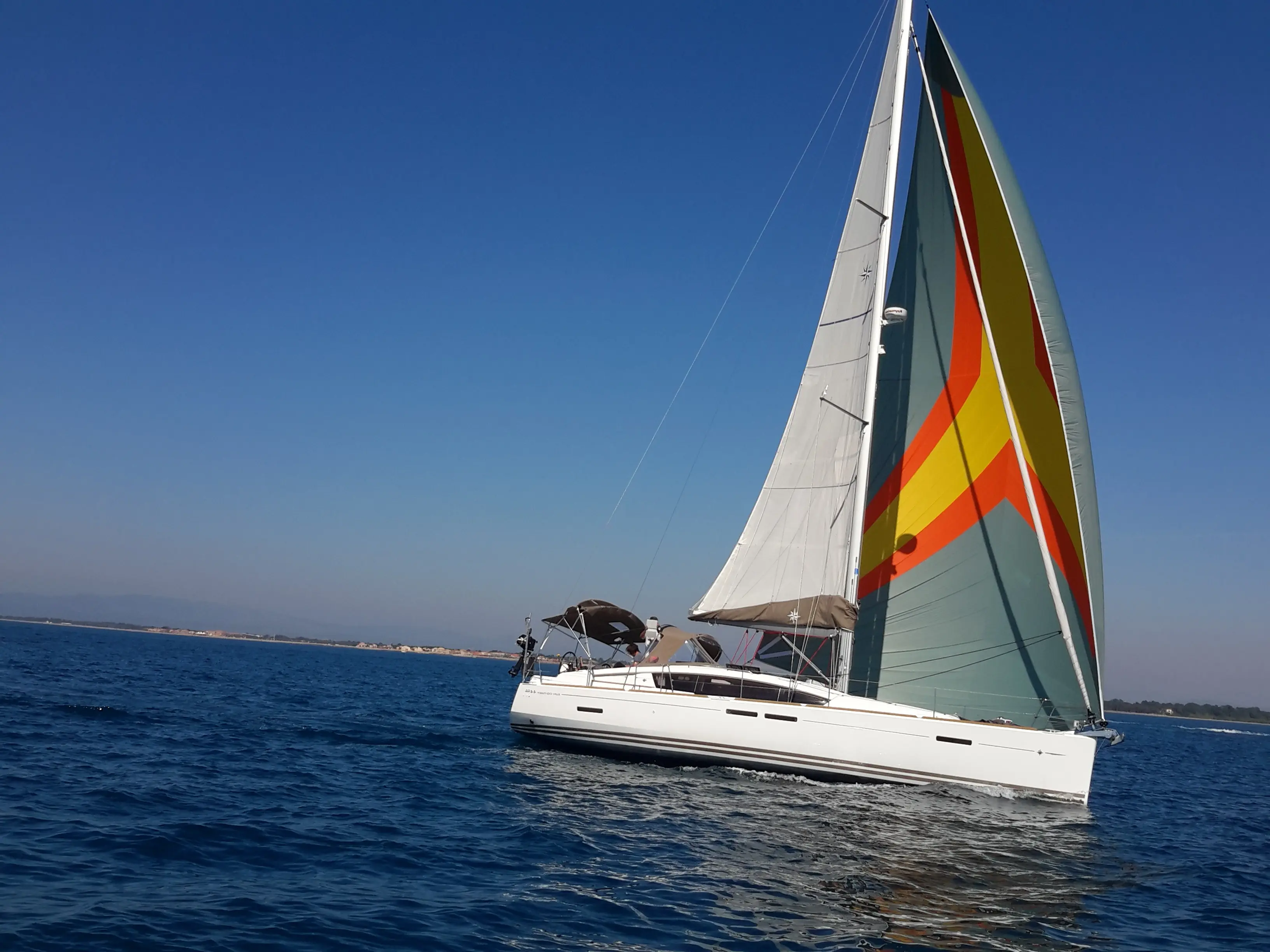 Jeanneau Sun Odyssey 44 Ds — Voilier blanc naviguant au large sous grand-voile et spinnaker coloré.