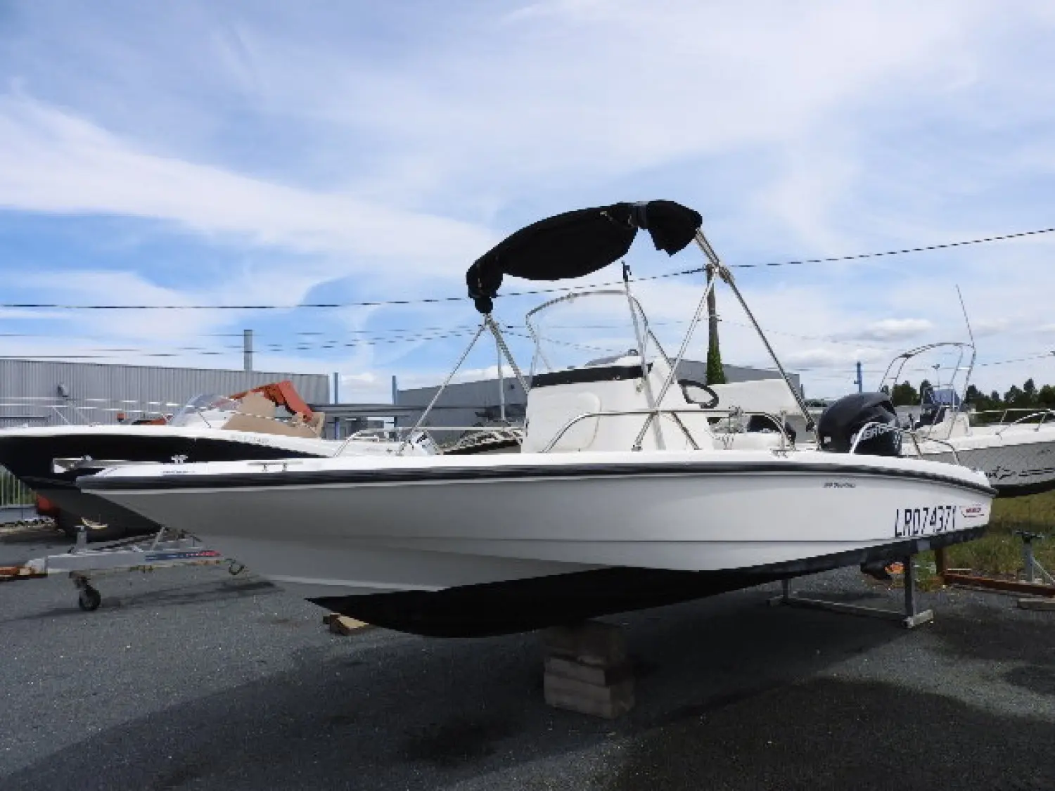 Boston Whaler 200 Dauntless — Bateau blanc à console centrale présenté sur remorque, vu de trois quarts.