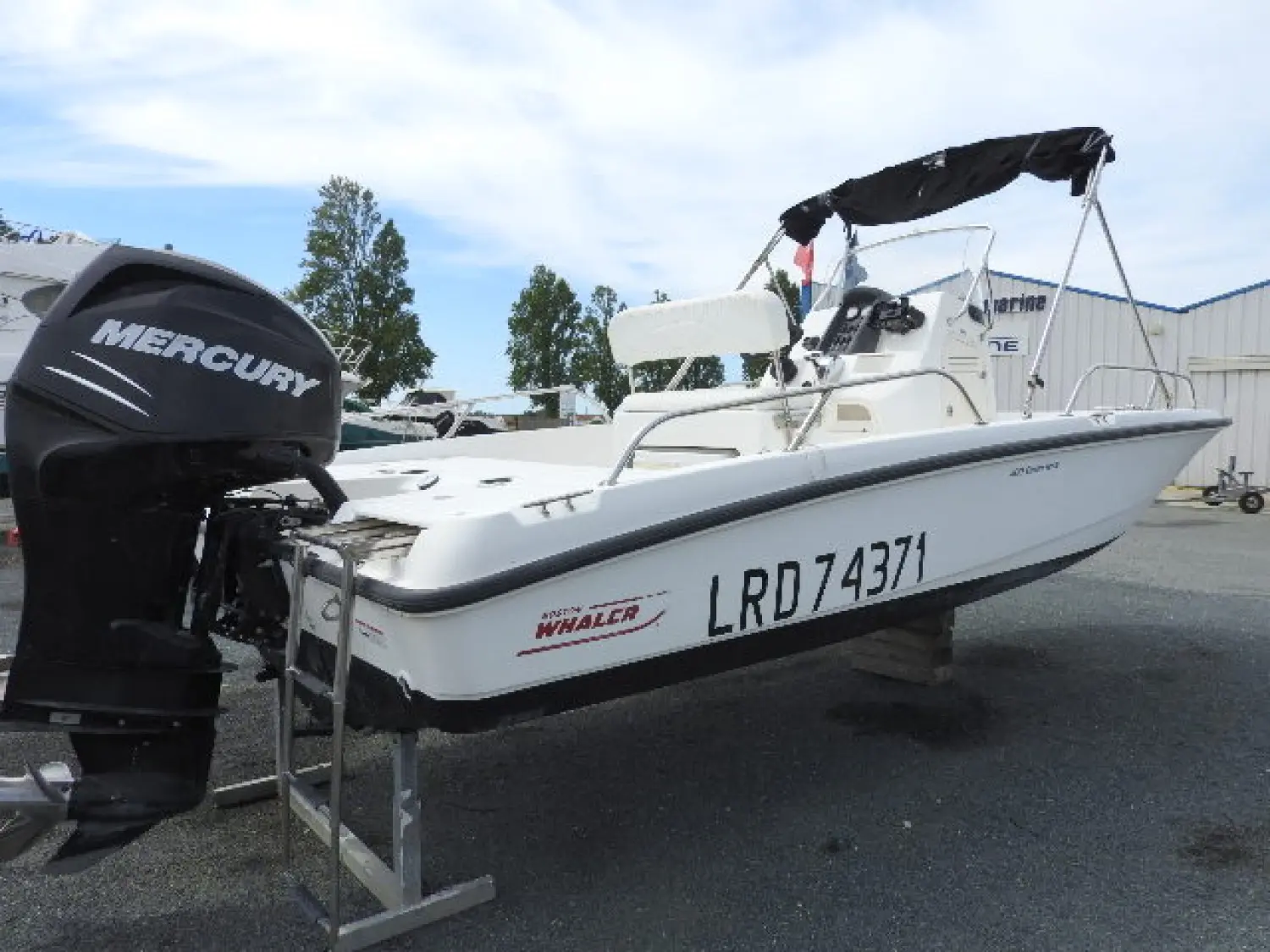 Boston Whaler 200 Dauntless — Bateau blanc à console centrale, photographié sur remorque dans une cour extérieure.