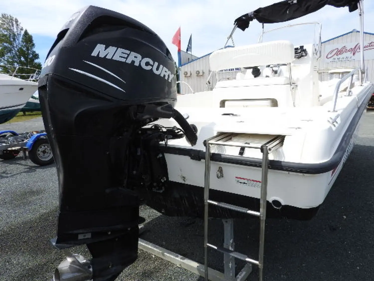Boston Whaler 200 Dauntless — Vue arrière d’un bateau blanc sur remorque, avec un moteur hors-bord noir.