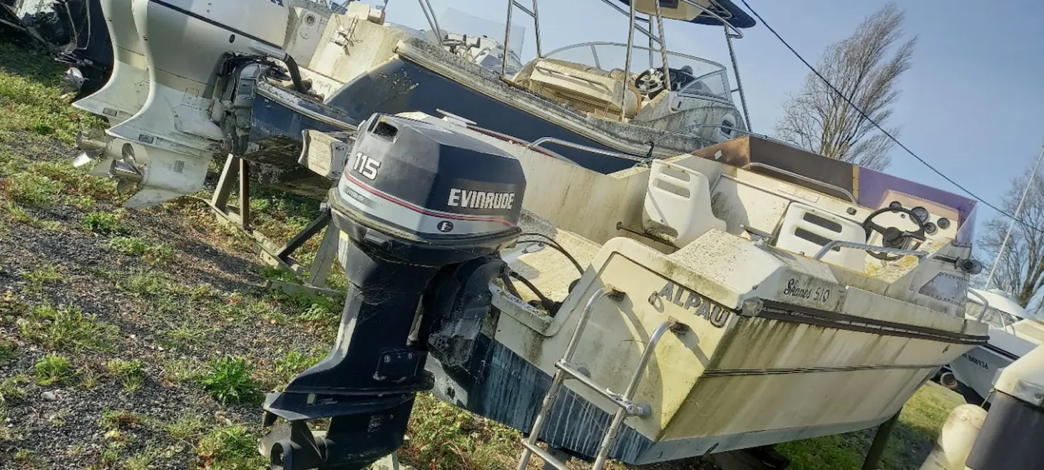 Jeanneau Skanes 510 — Vue arrière d’un petit bateau à moteur posé à terre, avec son moteur hors-bord visible.