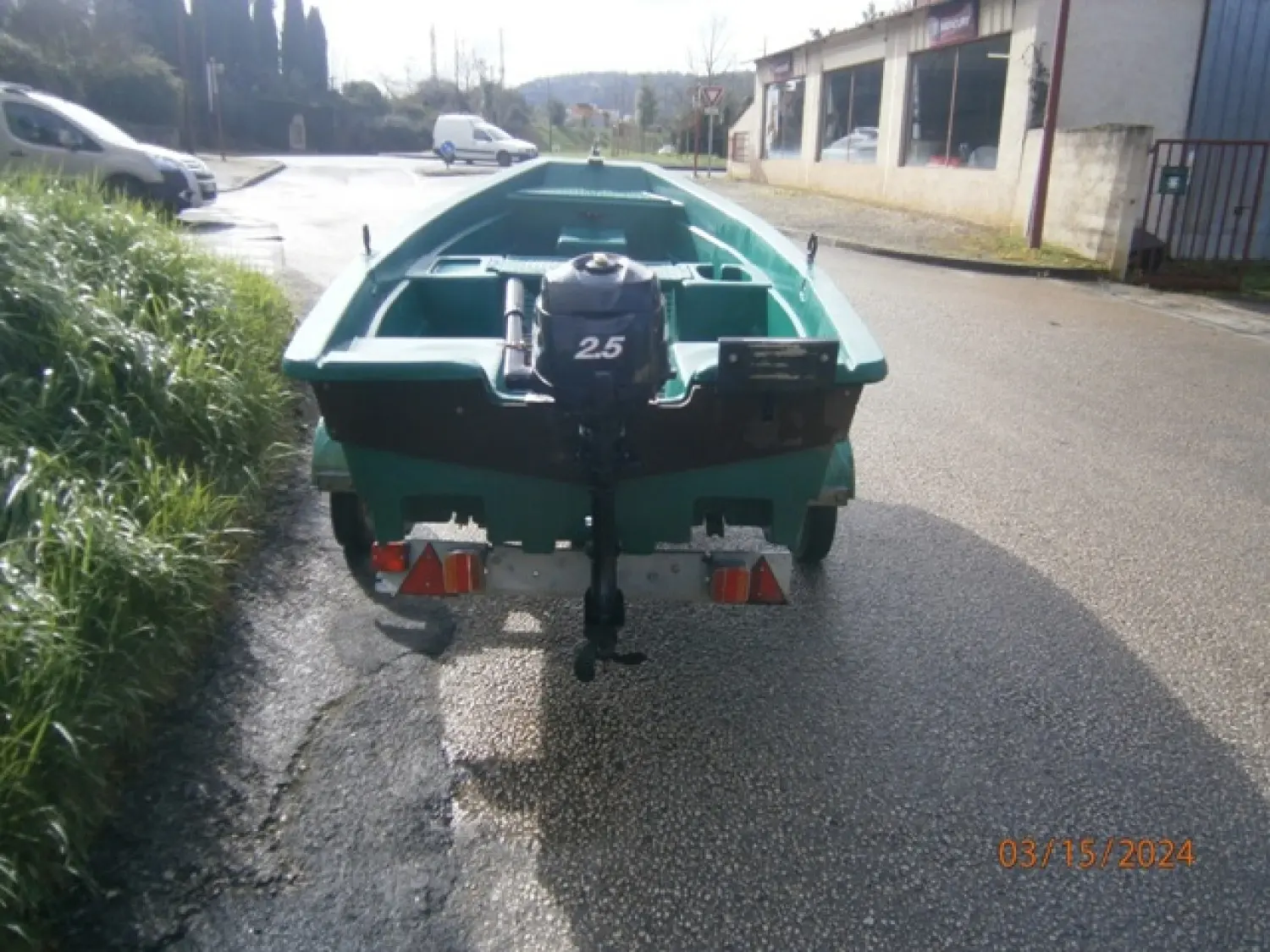 Armor 320 — Vue arrière d’une petite embarcation verte sur remorque, avec moteur hors-bord.