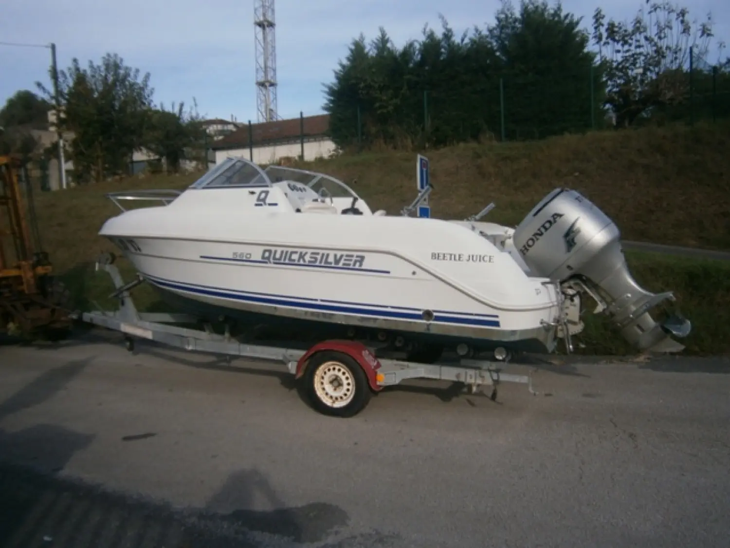 Quicksilver 560 — Bateau à moteur blanc photographié sur sa remorque, vu de profil.