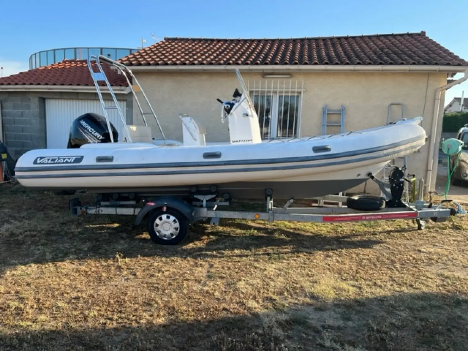 Valiant 580 Classic — Bateau pneumatique blanc présenté sur sa remorque devant une maison.