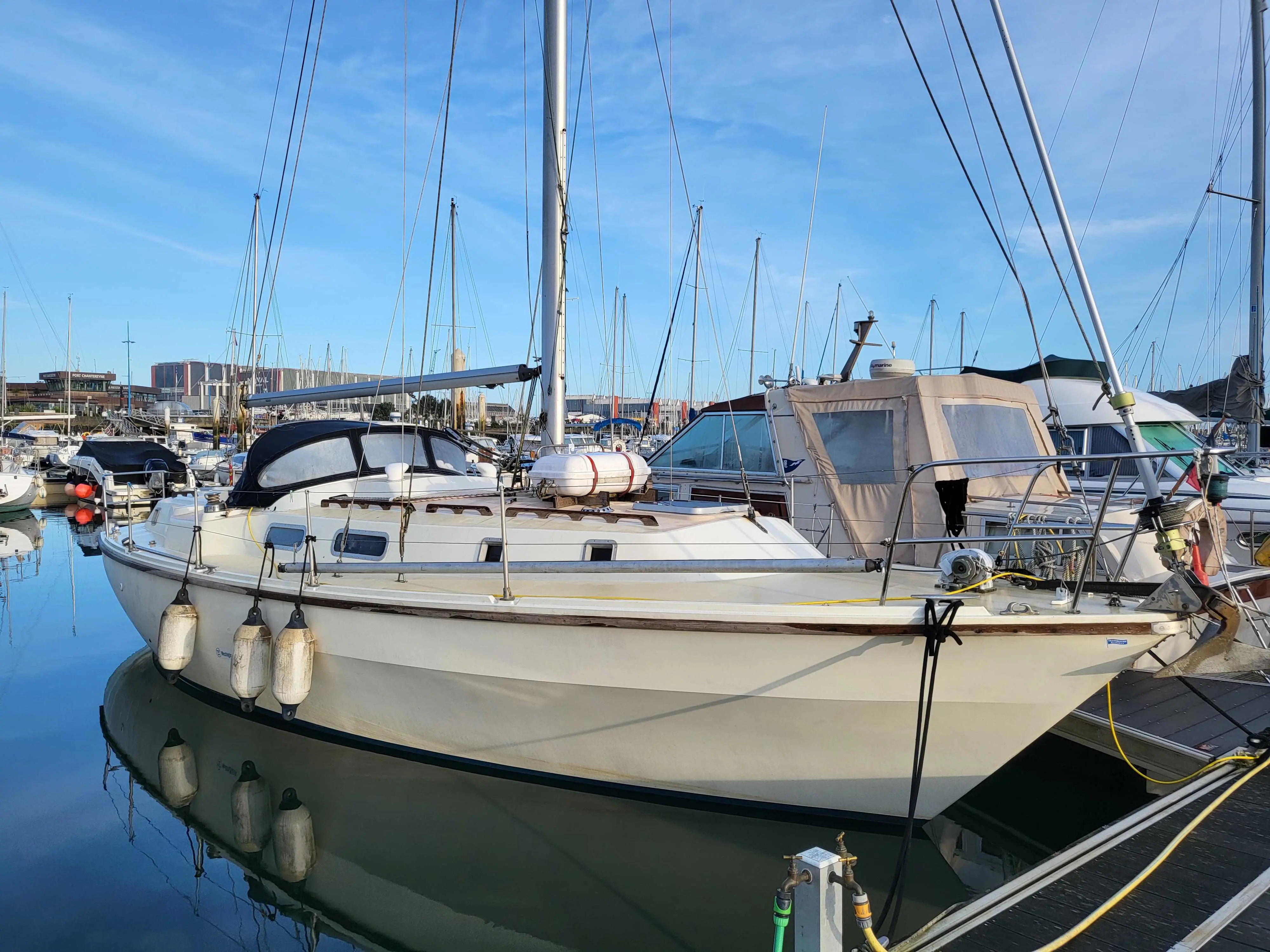 Westerly Discus — Voilier blanc amarré dans une marina, vu de trois quarts.