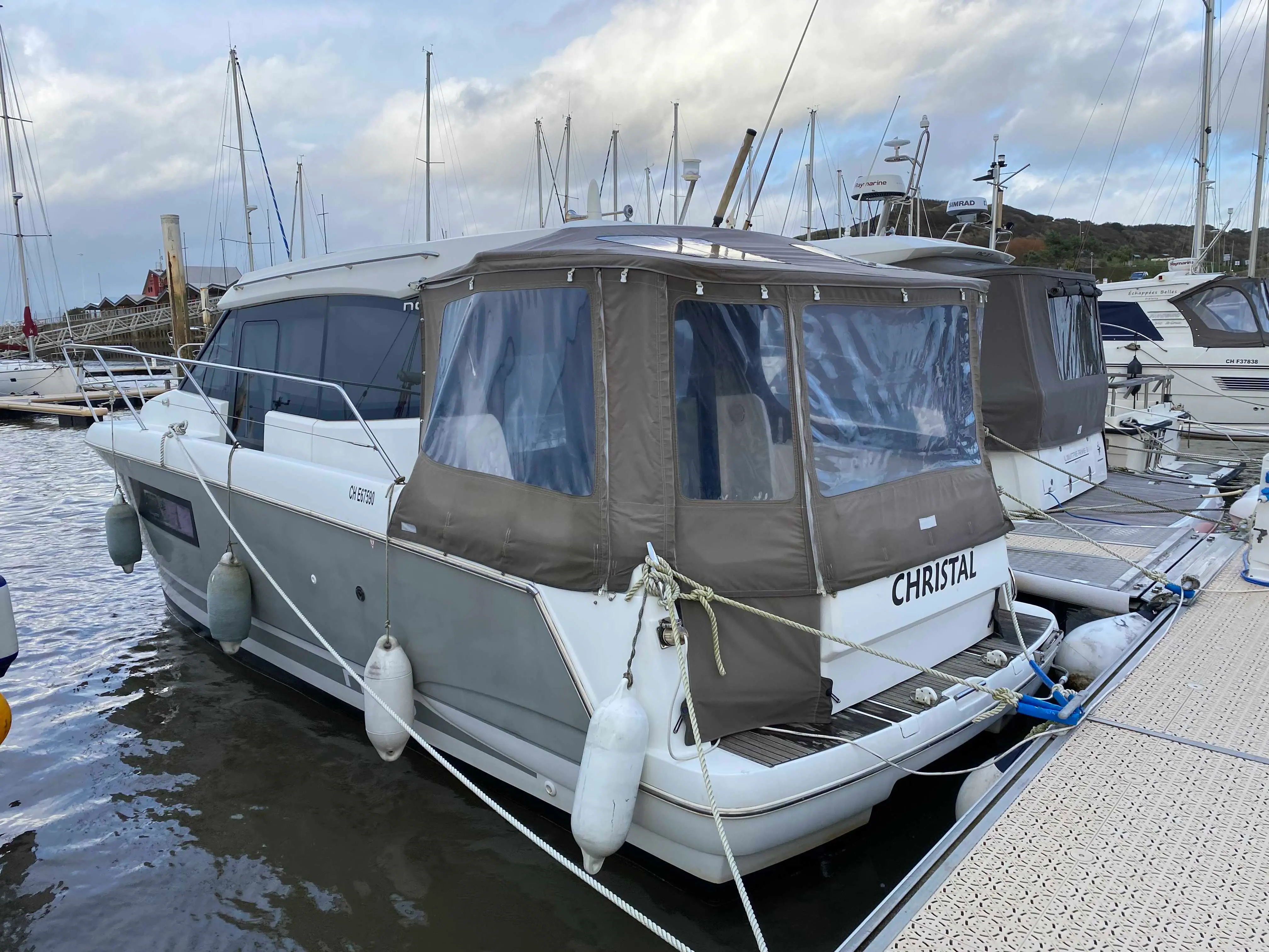 Jeanneau NC 9 — Bateau à moteur amarré, vu de trois quarts arrière dans un port.