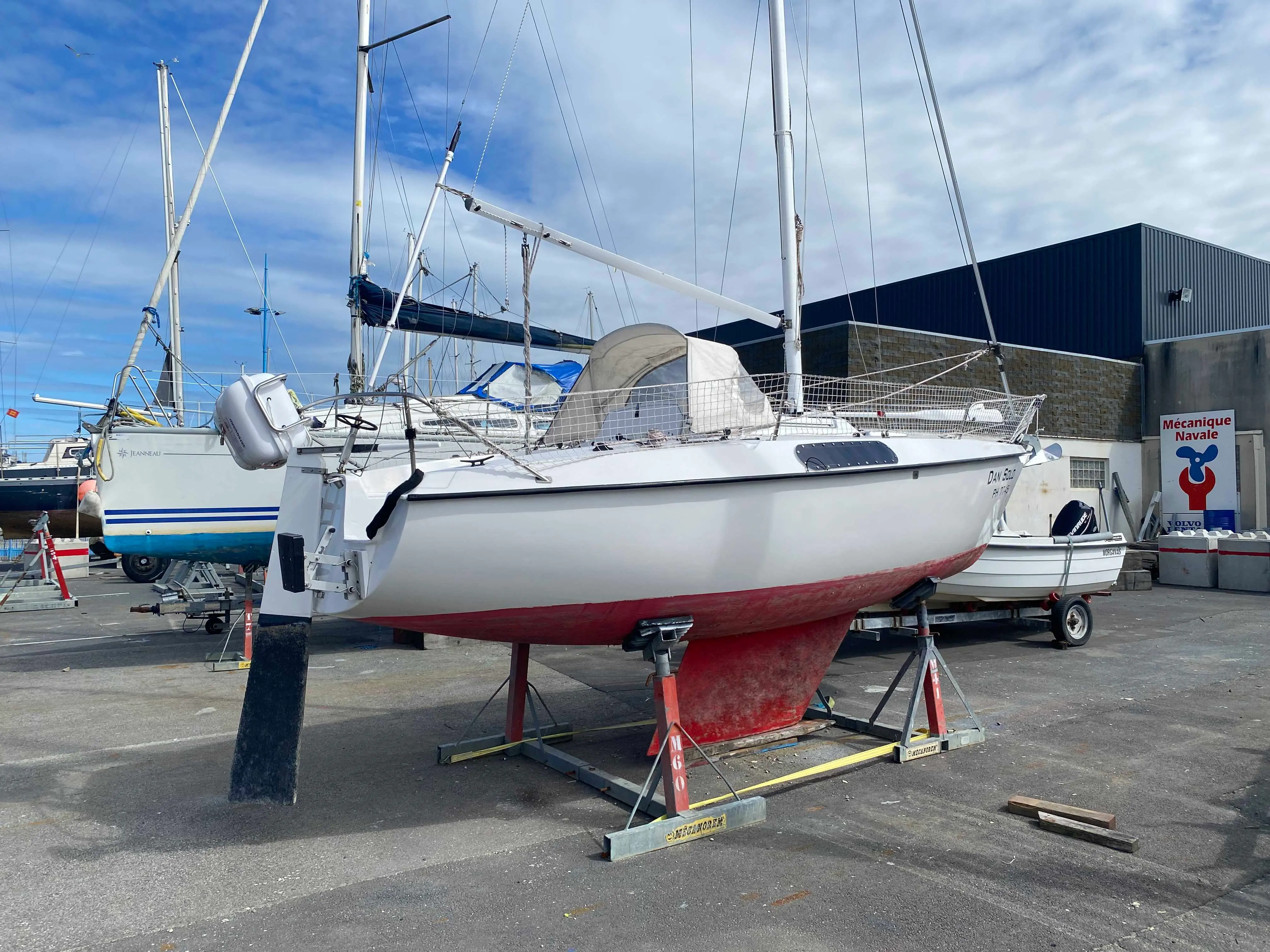 Kelt 620 — Voilier blanc présenté sur bers dans un chantier naval, vu de trois quarts avant.