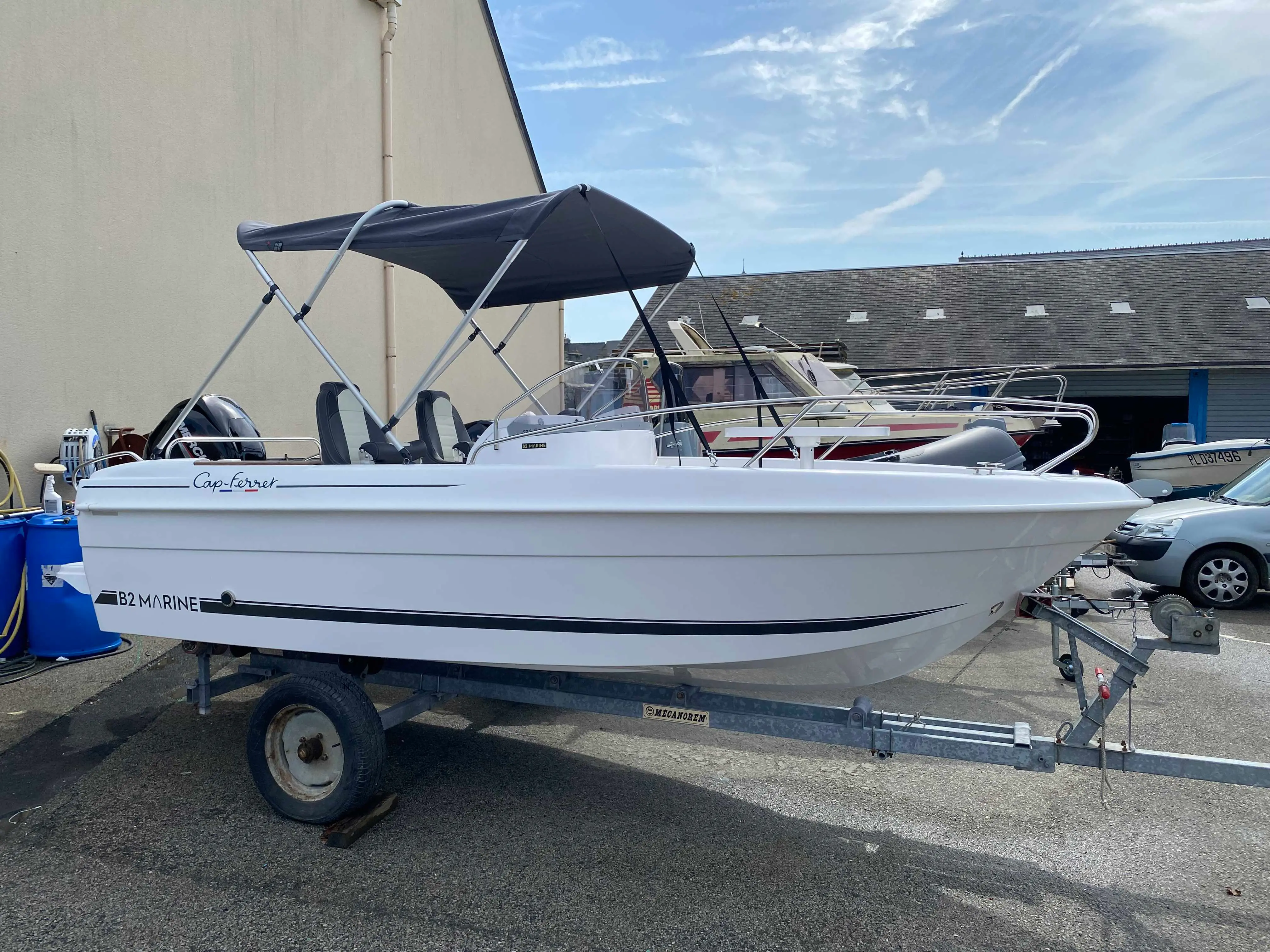 B2 Marine Cap Ferret 522 — Bateau à moteur blanc vu de profil sur remorque, avec taud et console centrale.