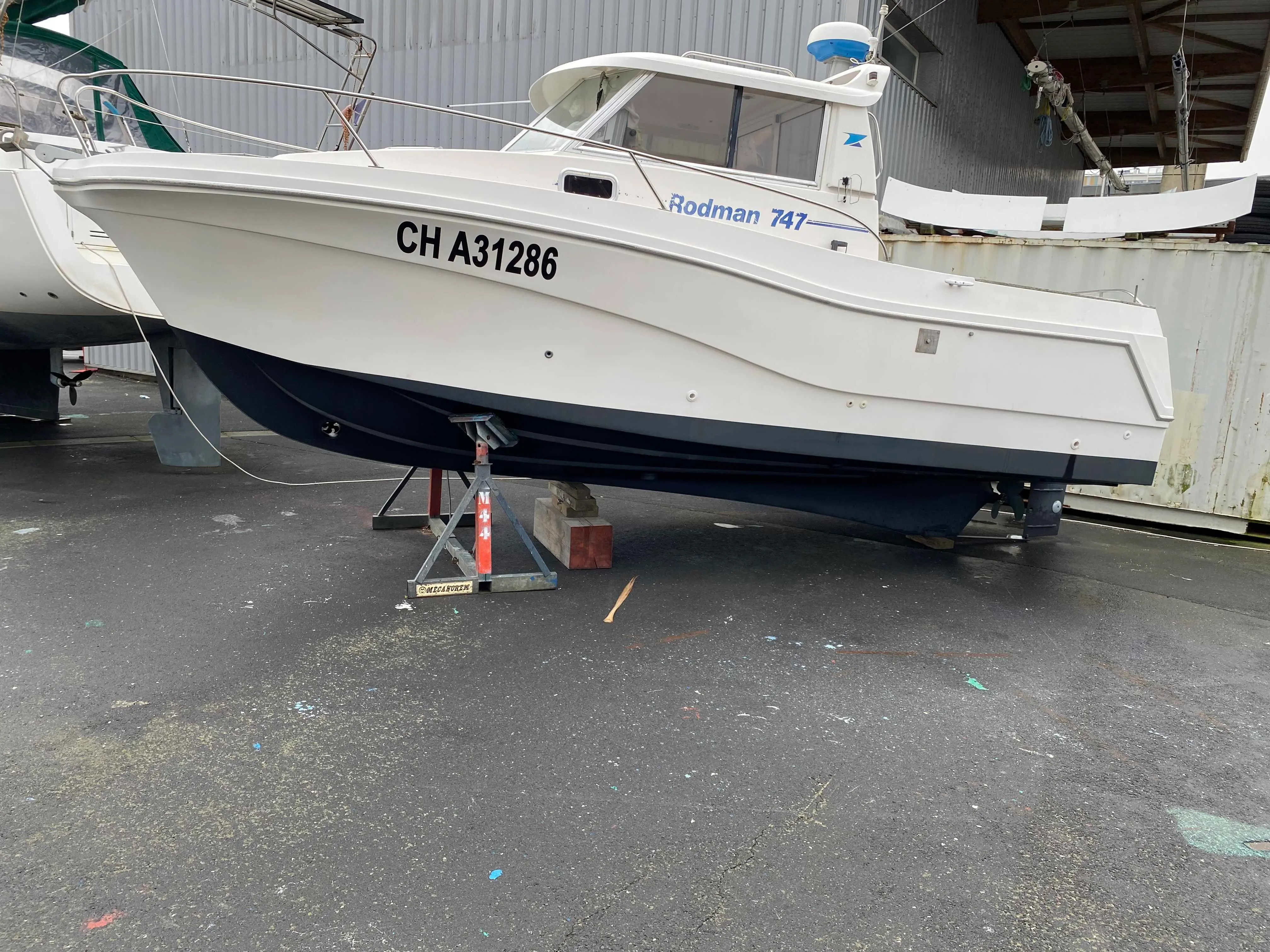 Rodman 747 — Bateau à moteur blanc vu de profil, posé sur ber et entouré d’autres embarcations.