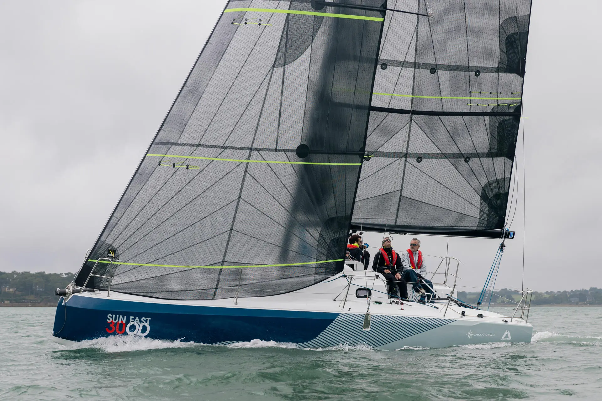 Jeanneau Sun Fast 30 — Voilier au près, toutes voiles hissées, avec trois personnes à bord.