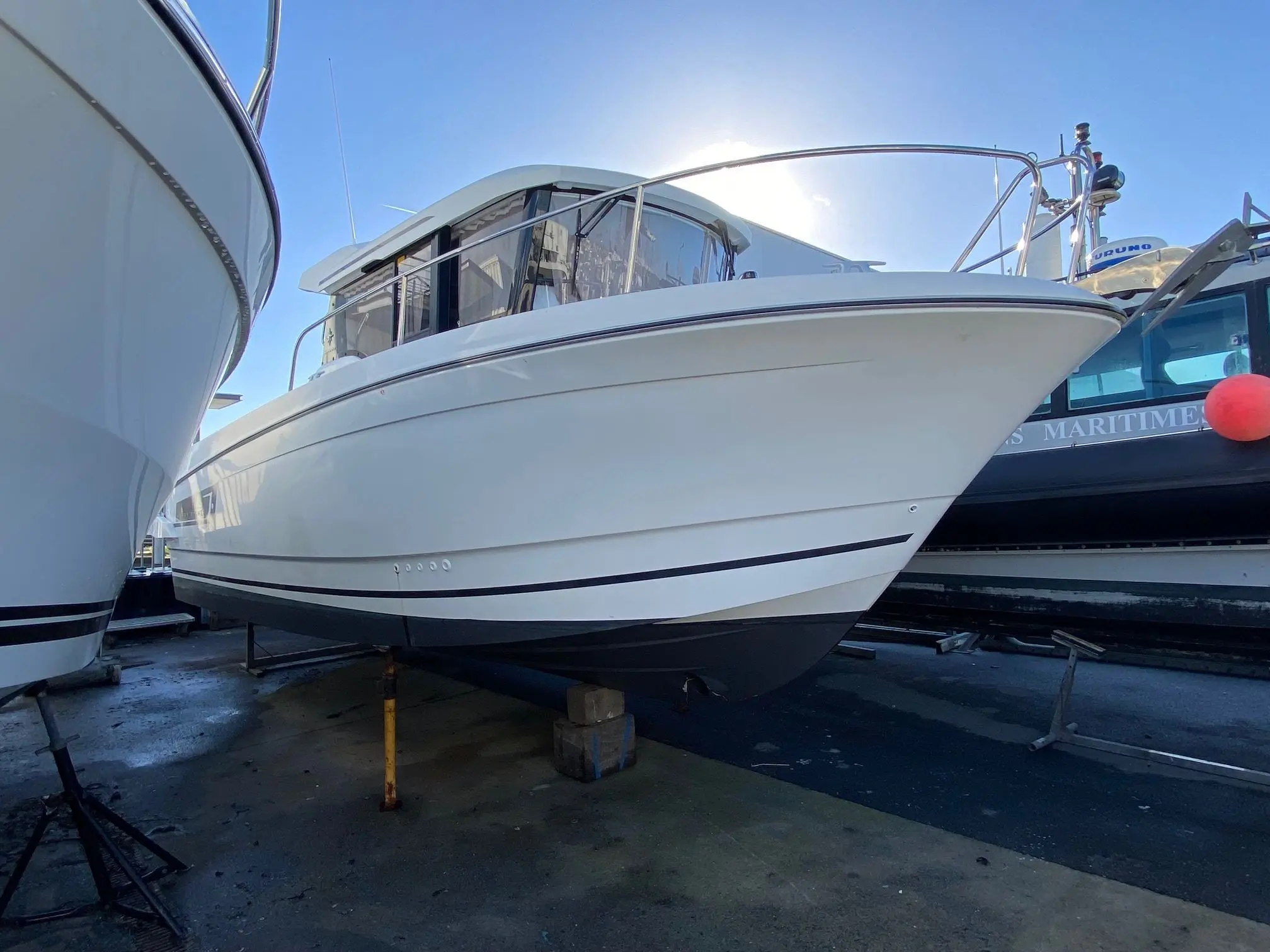 Jeanneau Merry Fisher 875 Marlin — Bateau blanc à cabine présenté sur berceau entre deux autres embarcations.